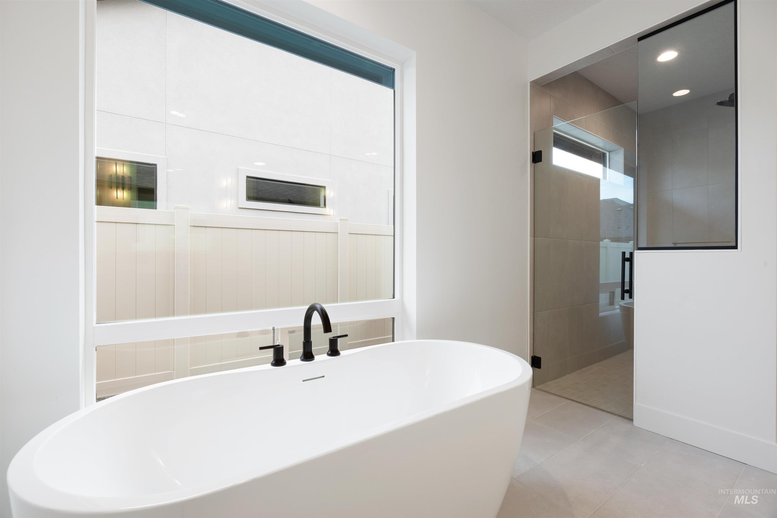 Full bath featuring a stall shower, a freestanding bath, recessed lighting, and light tile patterned floors