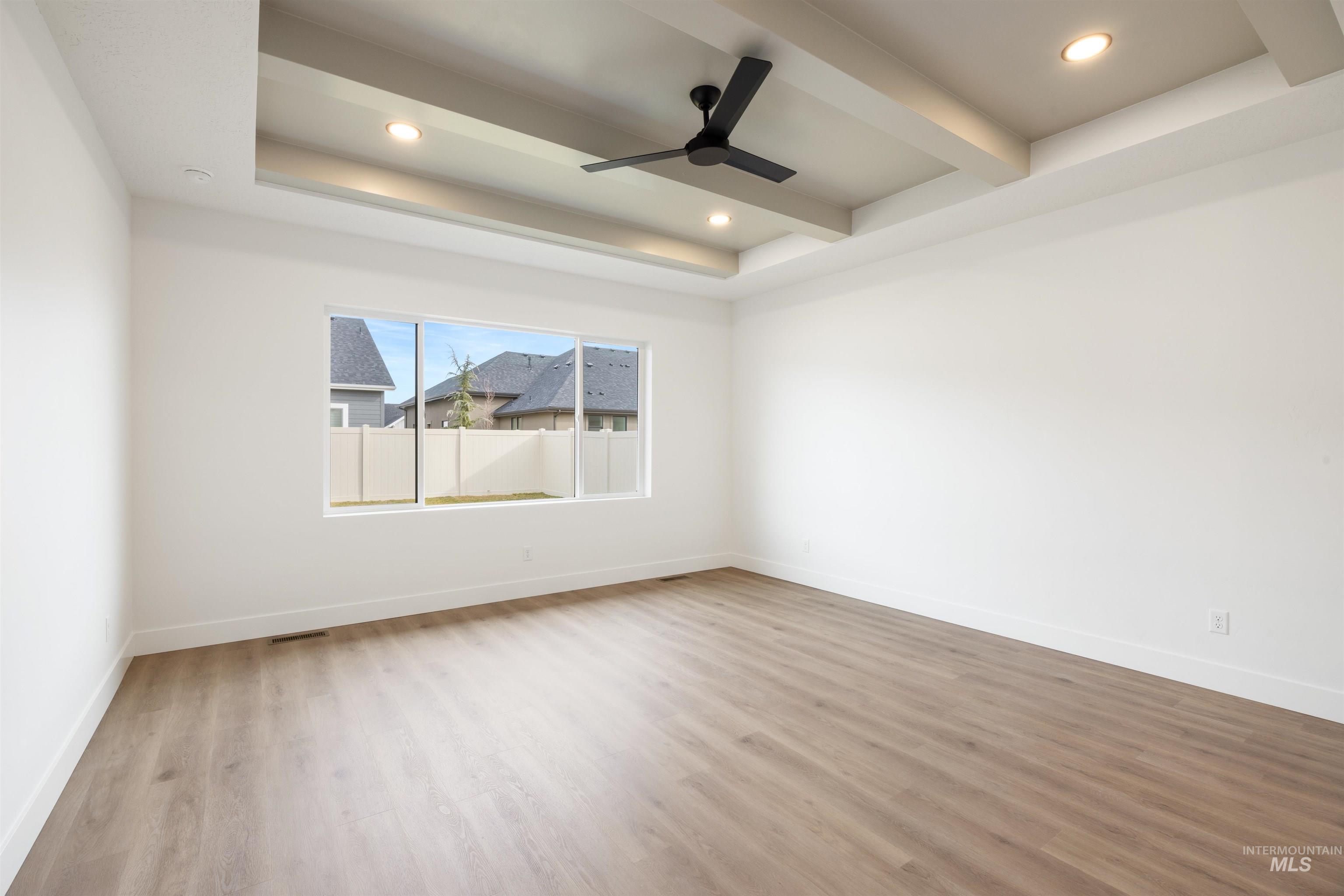 Spare room featuring a ceiling fan, light wood-style flooring, recessed lighting, and a tray ceiling