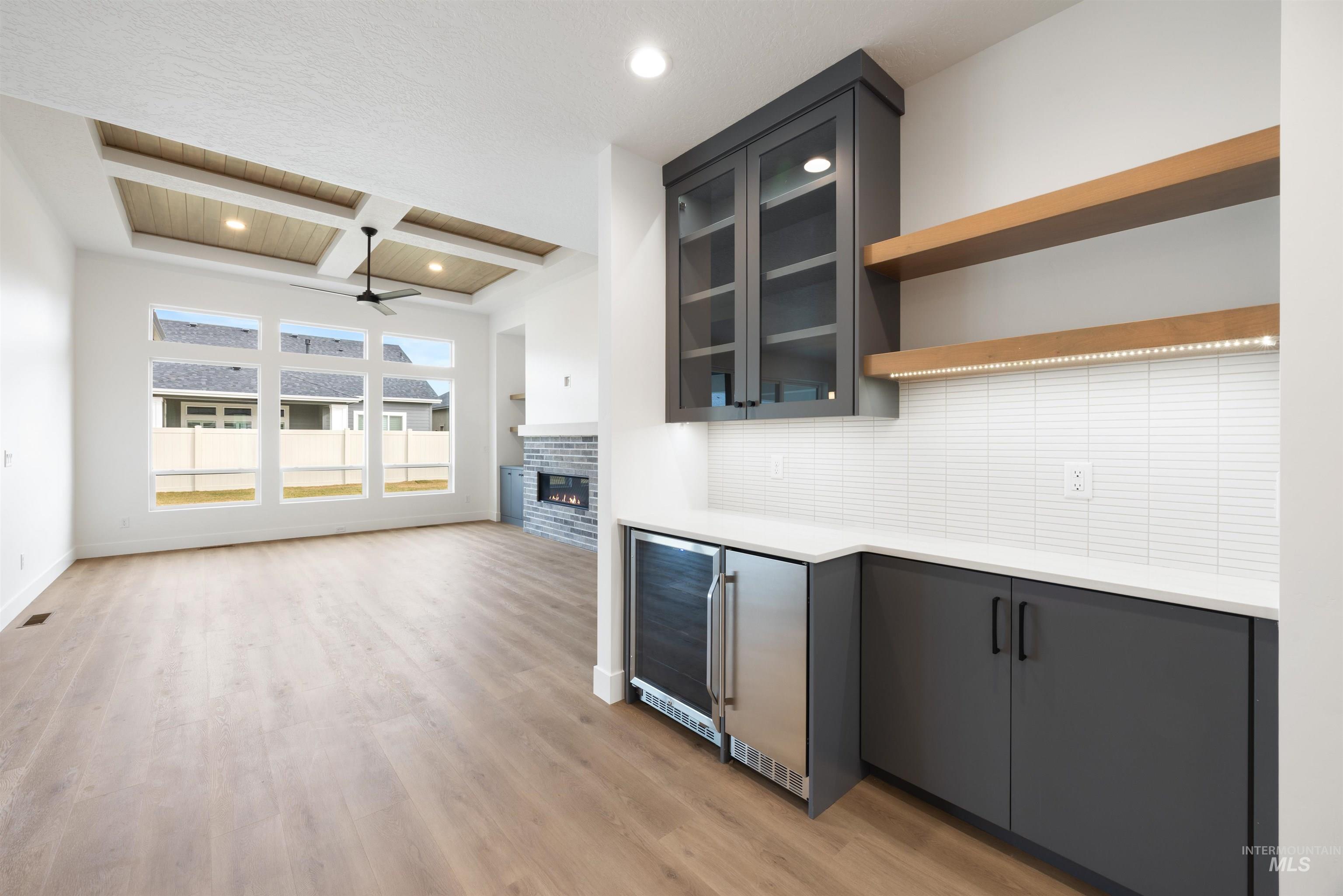 Kitchen featuring coffered ceiling, recessed lighting, backsplash, light wood-style floors, and beverage cooler