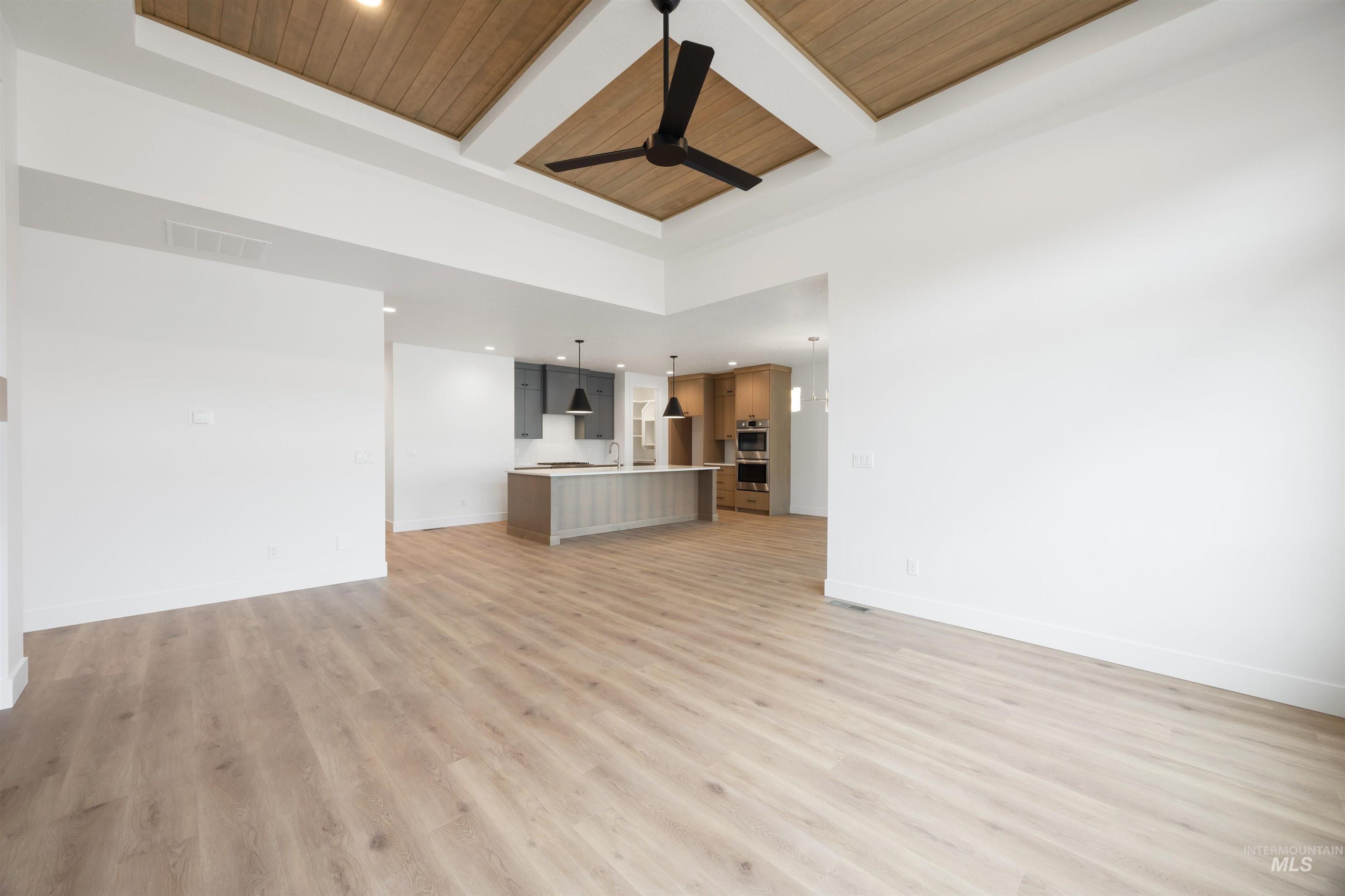 Unfurnished living room with recessed lighting, coffered ceiling, a high wooden beamed ceiling, light wood-style flooring, and ceiling fan