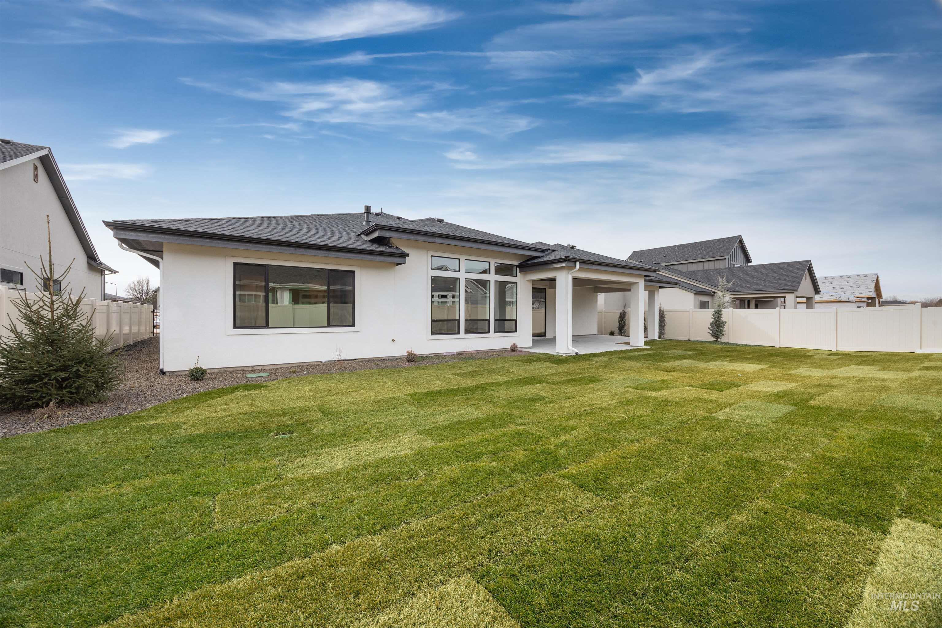 Rear view of property featuring a patio, stucco siding, and a shingled roof