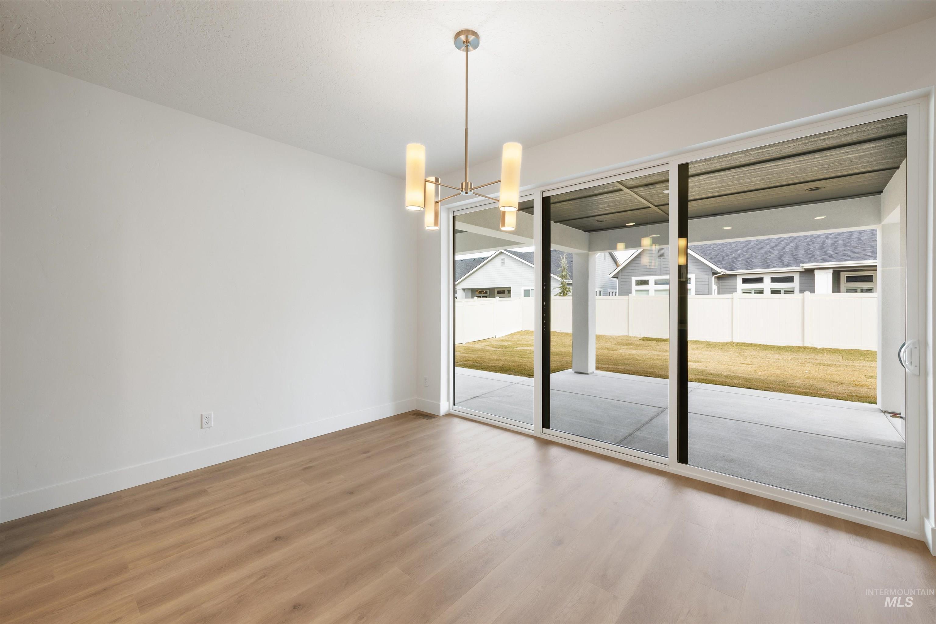 Unfurnished dining area with wood finished floors and suspended lighting