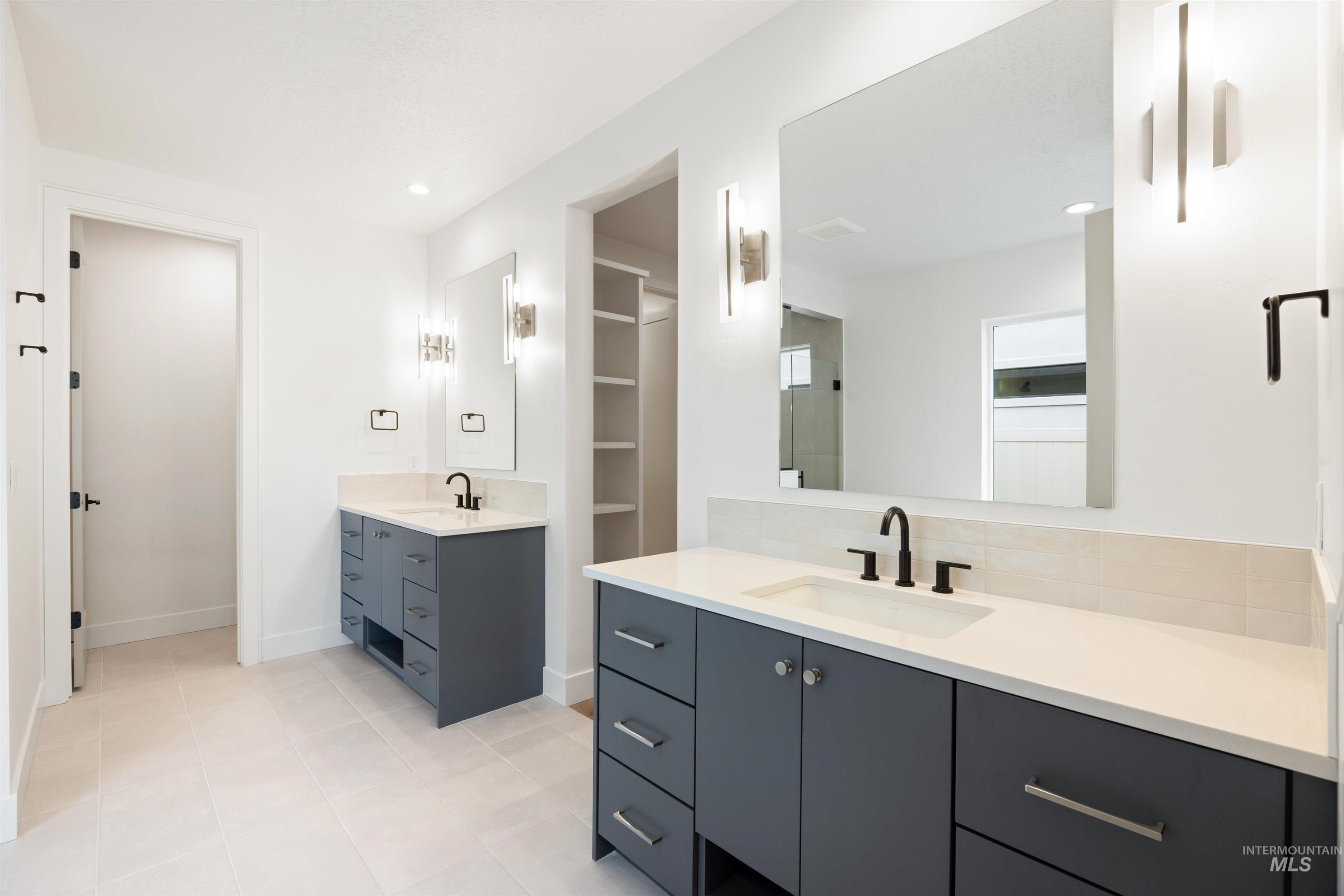 Bathroom featuring two vanities, light tile patterned flooring, and recessed lighting