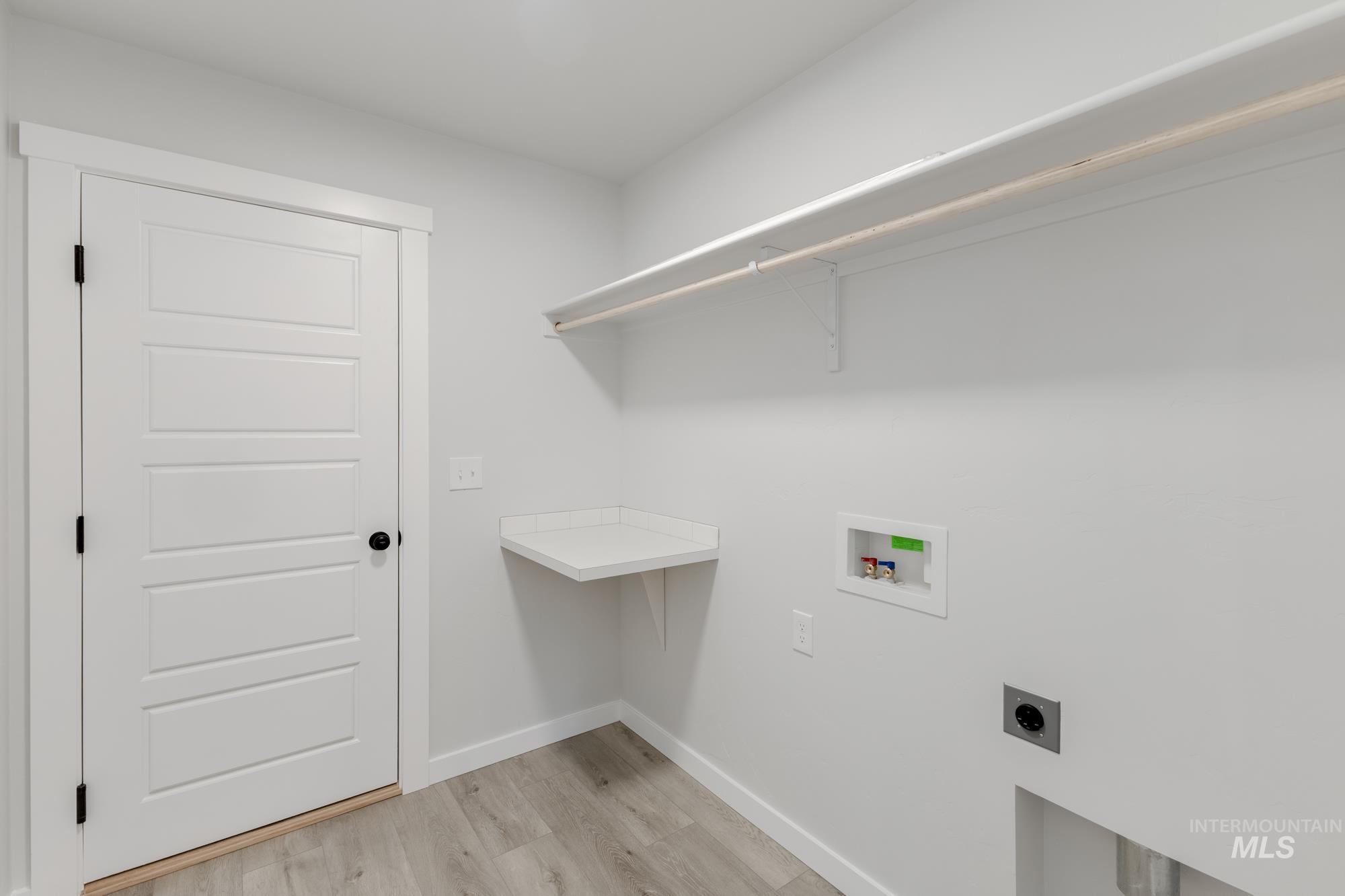 Laundry area with light wood finished floors, hookup for a washing machine, and hookup for an electric dryer