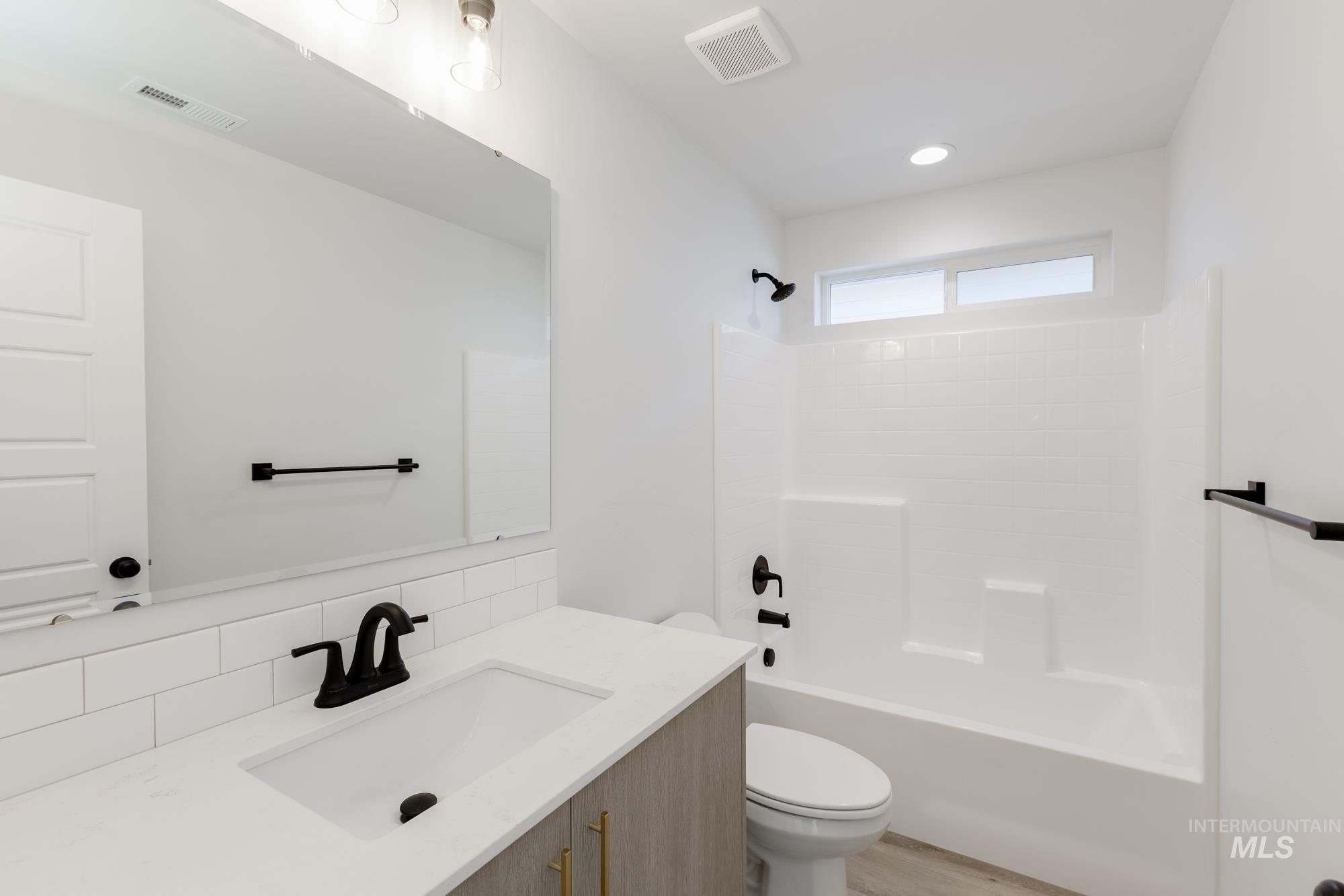 Bathroom featuring vanity, bathing tub / shower combination, and tasteful backsplash