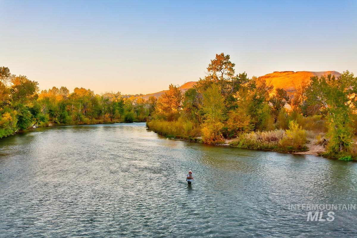 Riverfront property featuring a broad waterway, lush autumnal trees, and distant hills