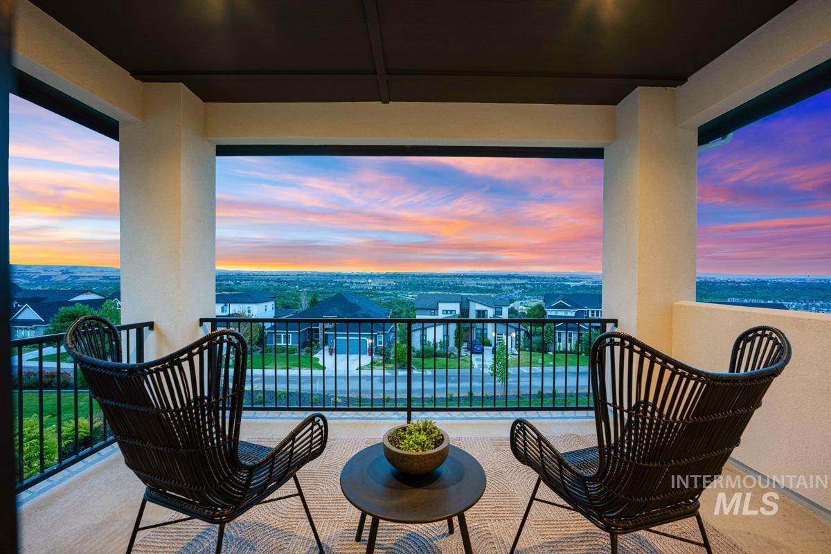 Covered balcony with expansive horizon scenery, featuring a black metal railing, smooth stucco walls, and recessed lighting