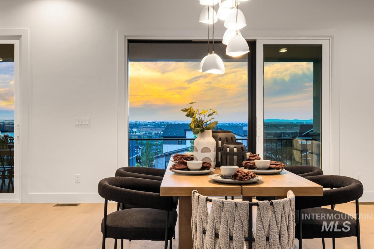 Dining area featuring light wood-finish flooring, a contemporary multi-pendant light fixture, and expansive glass sliding doors
