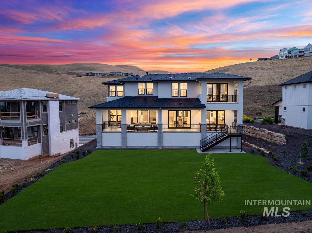 Modern rear exterior featuring a covered patio, upper balcony, and a landscaped yard