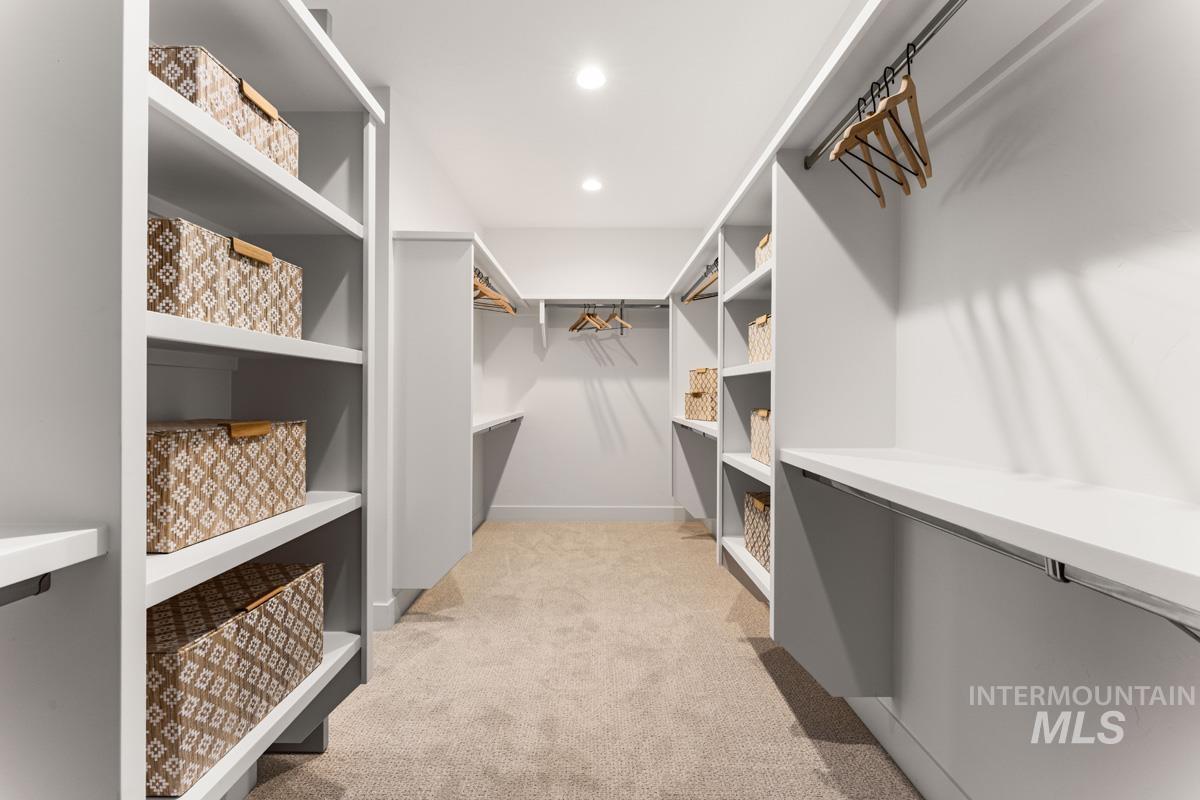 Spacious walk-in closet featuring extensive built-in shelving, hanging rods, and recessed lighting