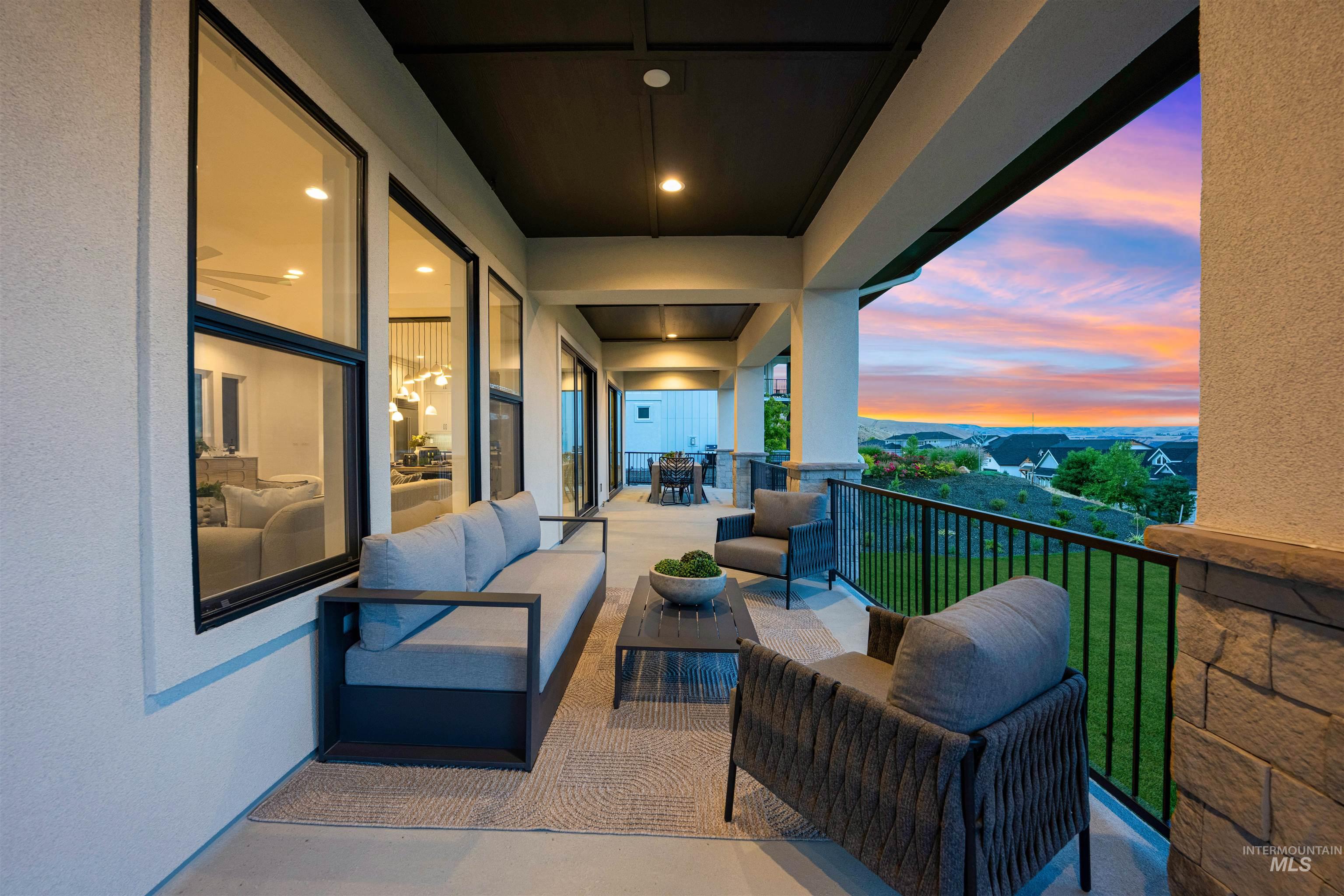 Expansive covered patio featuring recessed lighting, a black wrought-iron railing, and a stucco and stone pillar