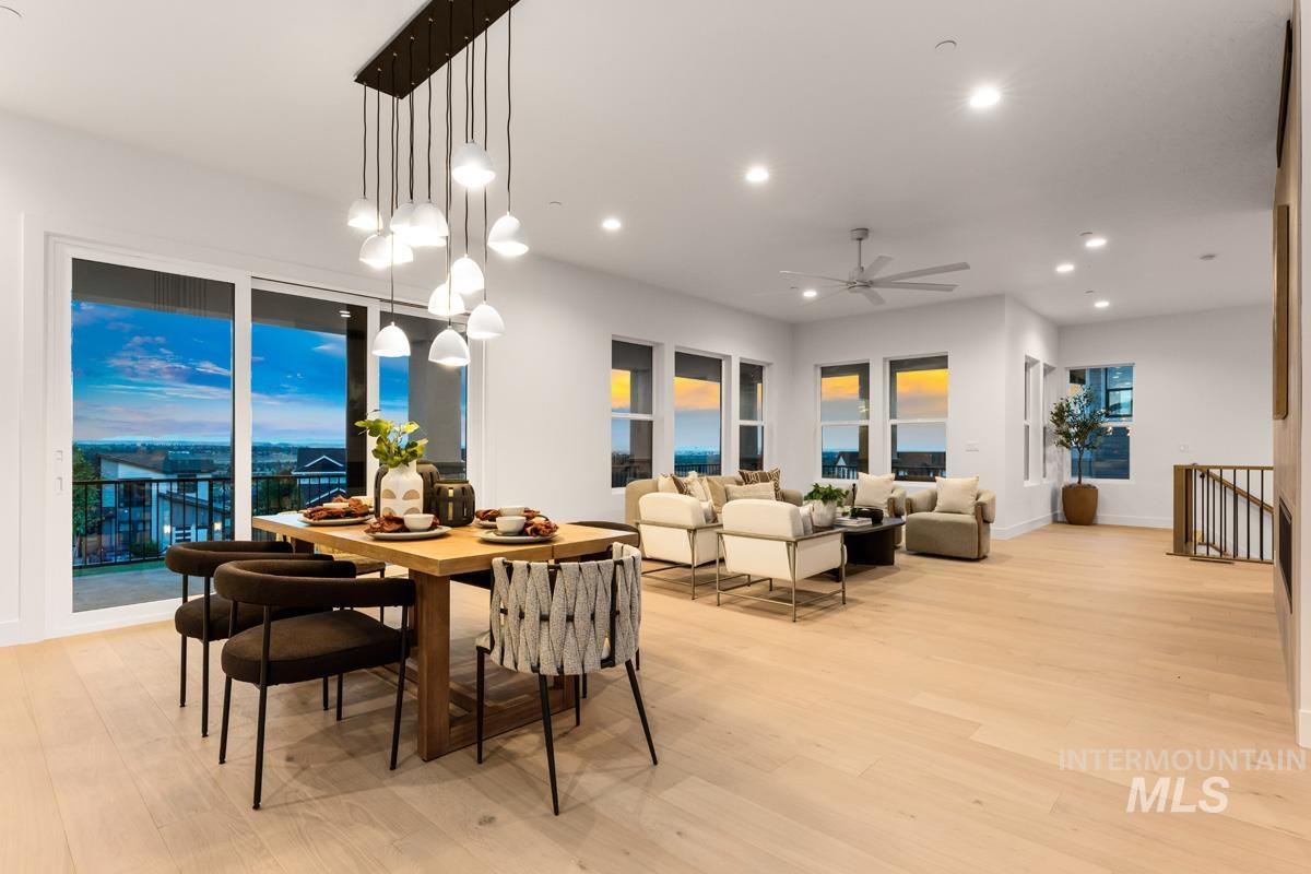 Open-concept living space featuring wood-finish flooring throughout, a linear multi-pendant light fixture, recessed ceiling lighting, and a ceiling fan