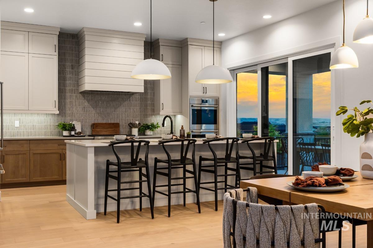 Open-concept kitchen featuring a center island with seating, pendant lighting, built-in stainless steel appliances, and a tiled backsplash