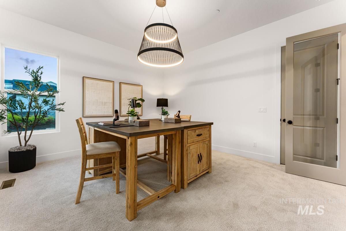 Bright room featuring a large window, soft carpet flooring, a tiered pendant light fixture, and a glass-paneled door
