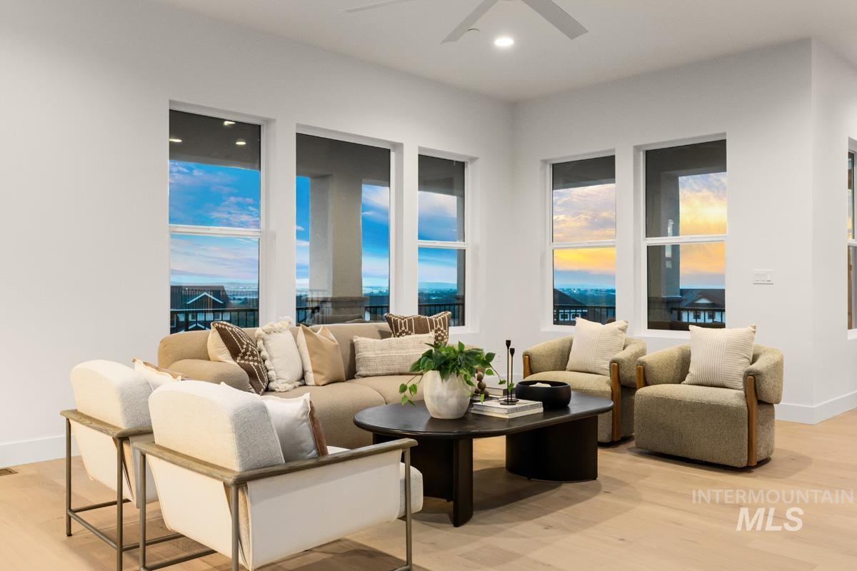 Living area featuring multiple large windows, light wood-finish flooring, recessed lighting, and a ceiling fan
