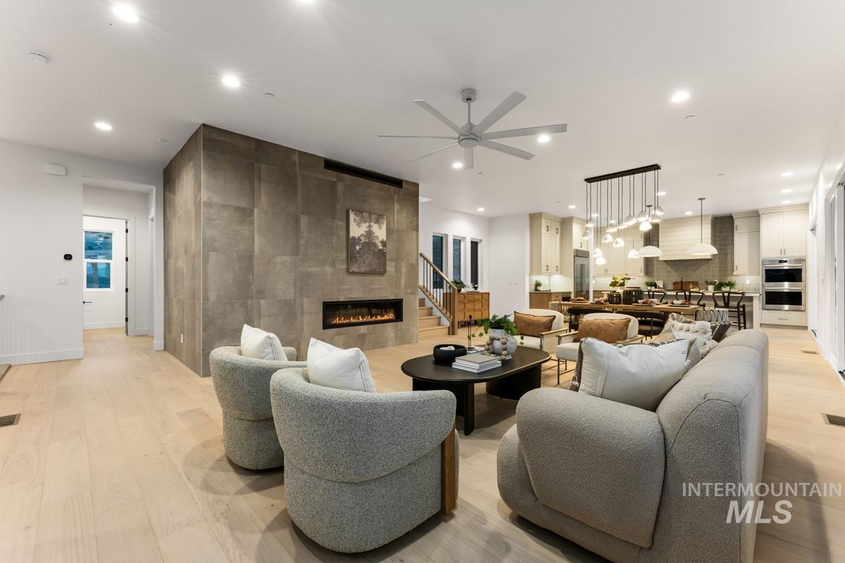 Open-concept living area with light wood-finish flooring, recessed lighting, and a modern ceiling fan