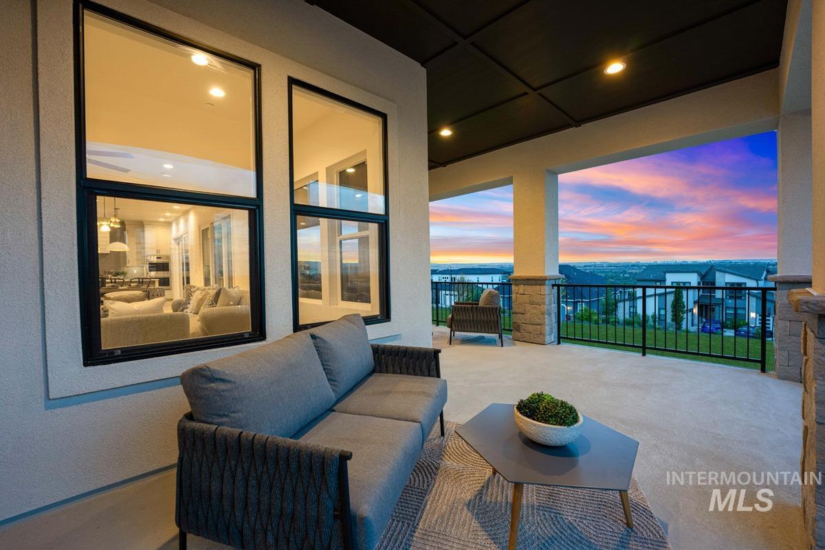 Expansive covered patio with concrete flooring, stone-clad pillars, and a black metal railing
