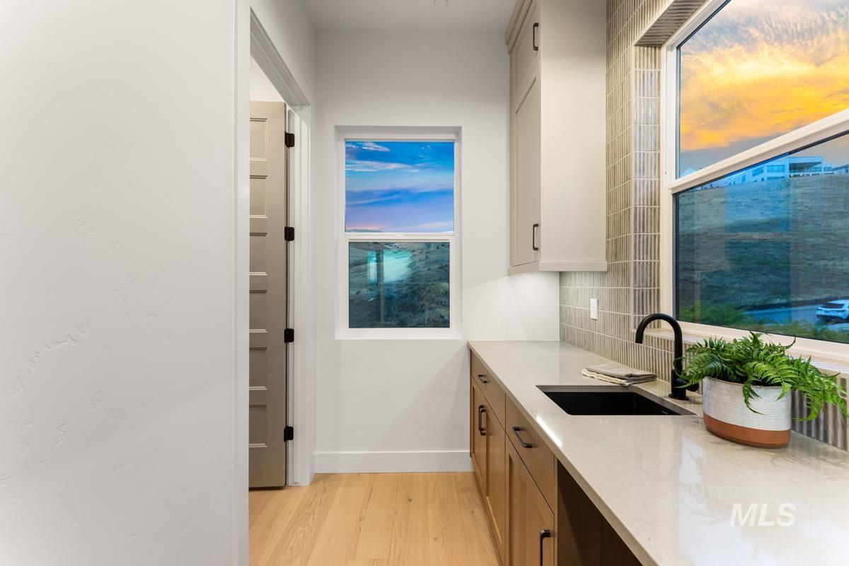 Utility area featuring light wood-finish flooring, a contemporary black sink, and a light-toned countertop