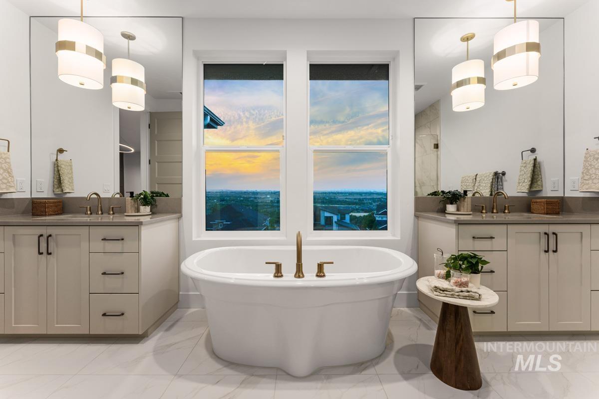 Freestanding soaking tub with gold-tone fixtures, complemented by dual vanities featuring quartz countertops and integrated sinks