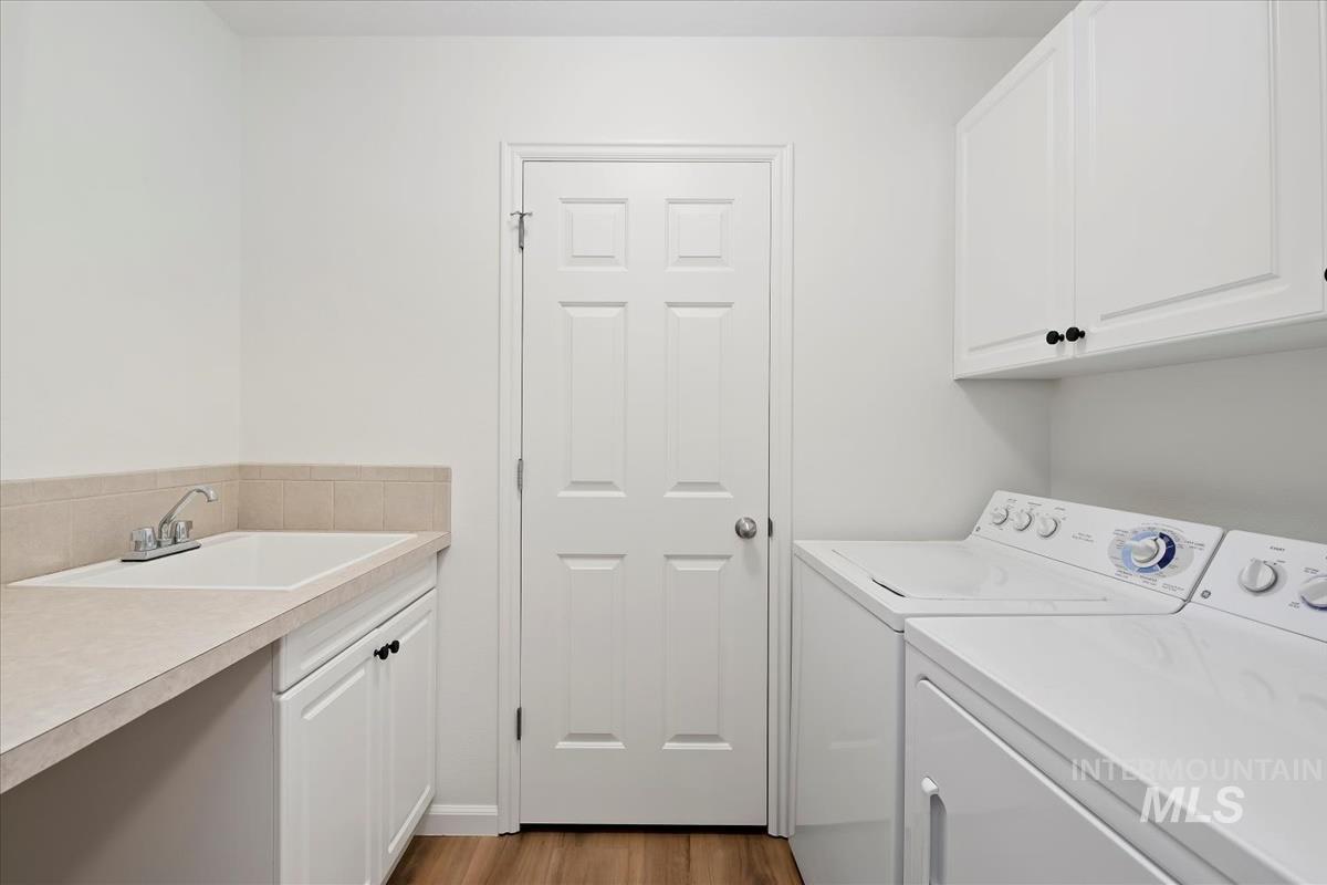 Laundry room featuring washing machine and dryer, cabinet space, and LVP flooring