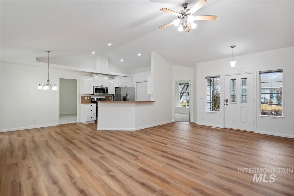 Living room with light LVP floors, ceiling fan, high vaulted ceiling, a chandelier, and recessed lighting