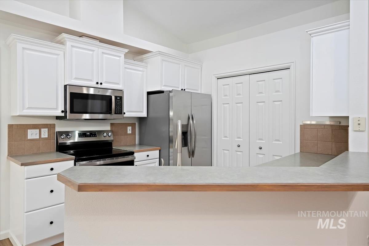 Kitchen with light countertops, appliances with stainless steel finishes, and white cabinets
