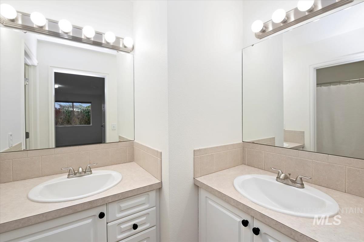 Full bathroom with vanity, backsplash, and a shower with curtain