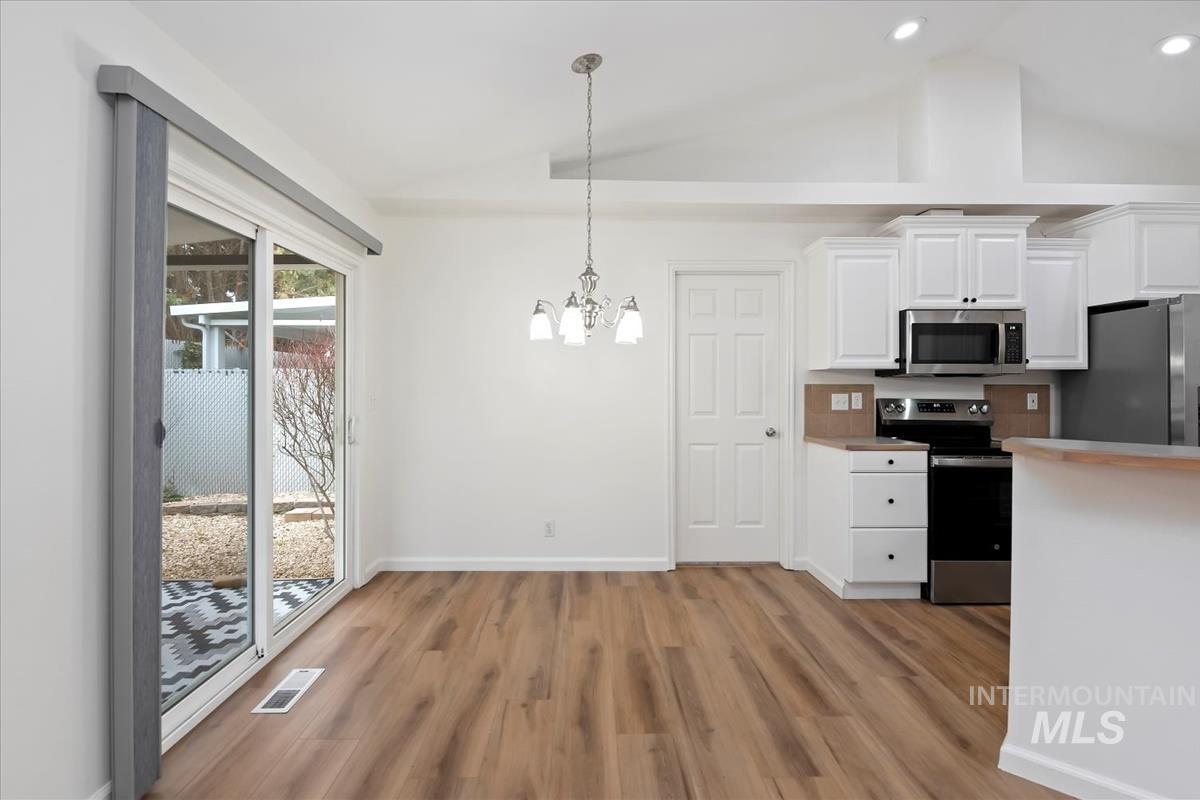 Dining area with vaulted ceiling with pendant lighting, and a chandelier
