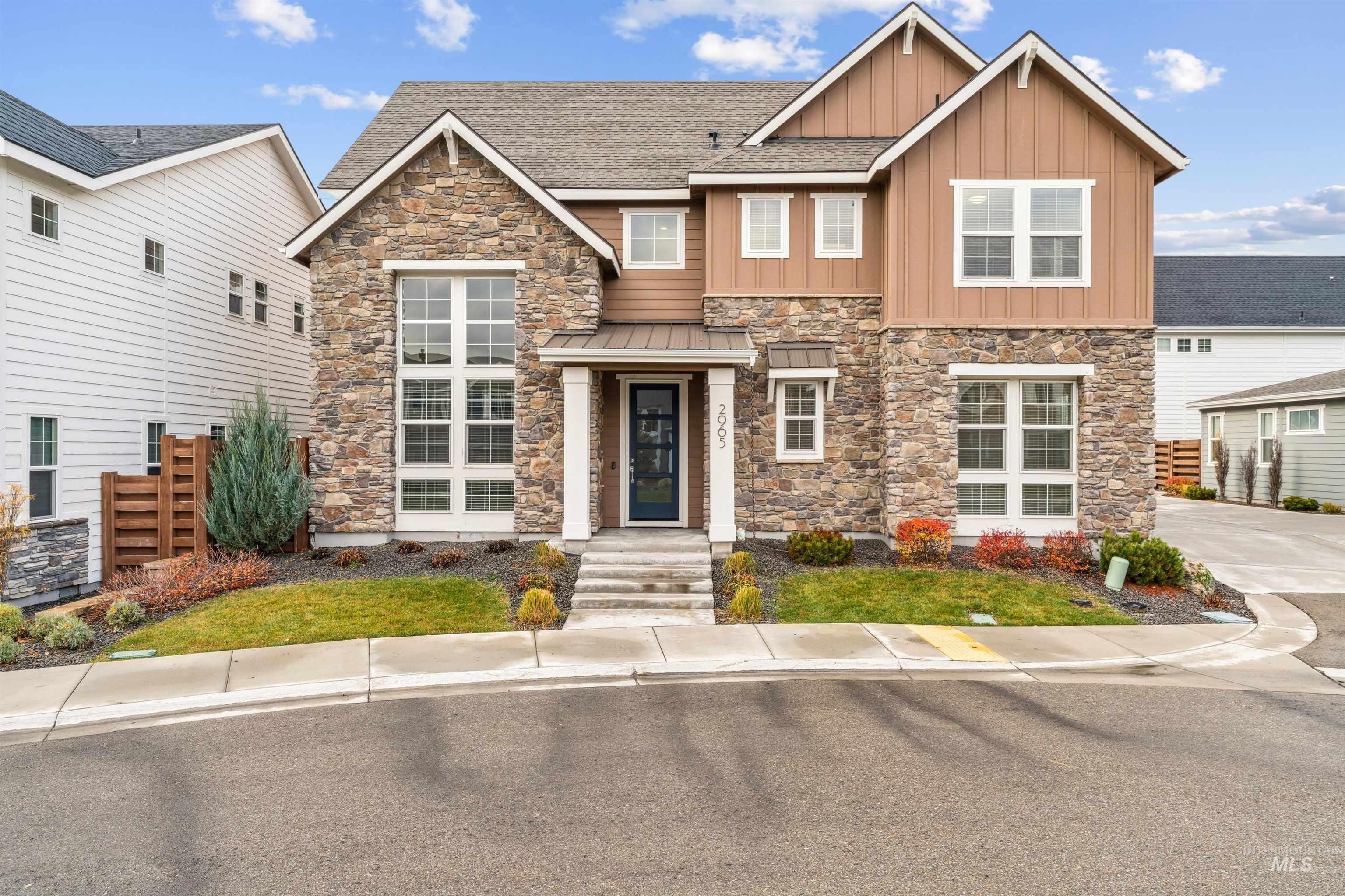 Craftsman-style house with stone siding, board and batten siding, a shingled roof, and a metal roof