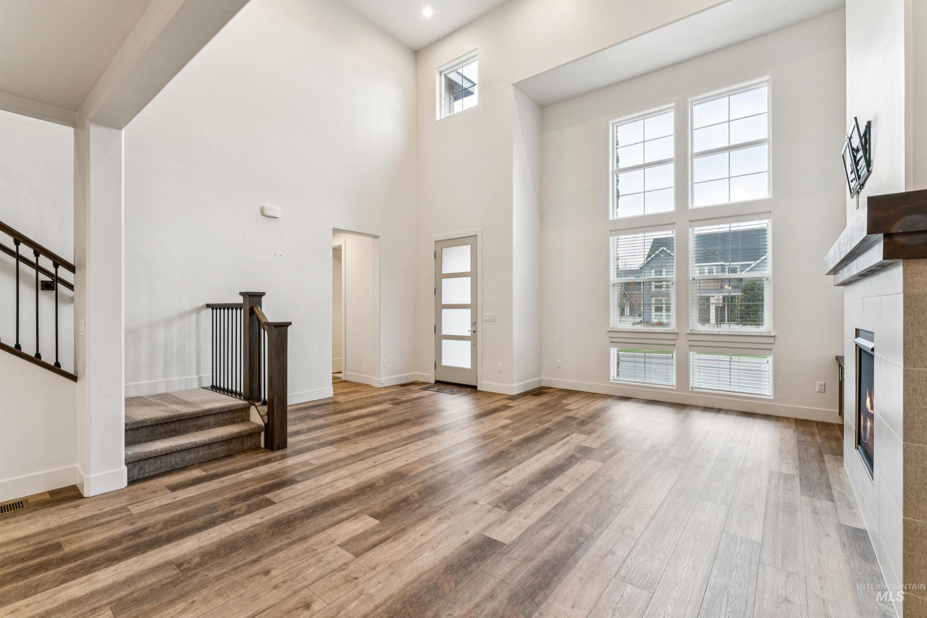Living room with a tile fireplace, luxury vinyl plank, a towering ceiling, and stairway