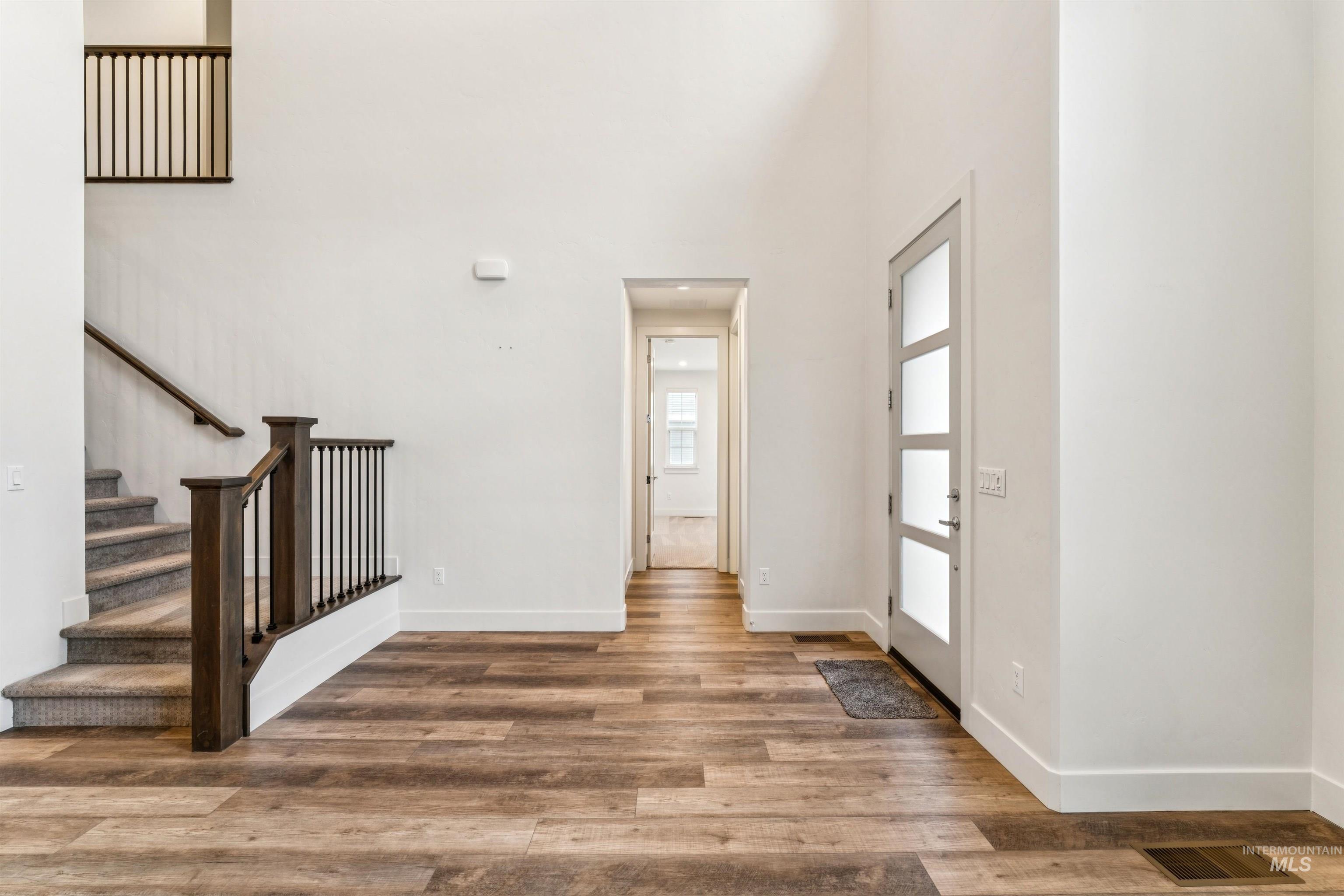 Foyer featuring stairs, luxury vinyl plank, and a towering ceiling