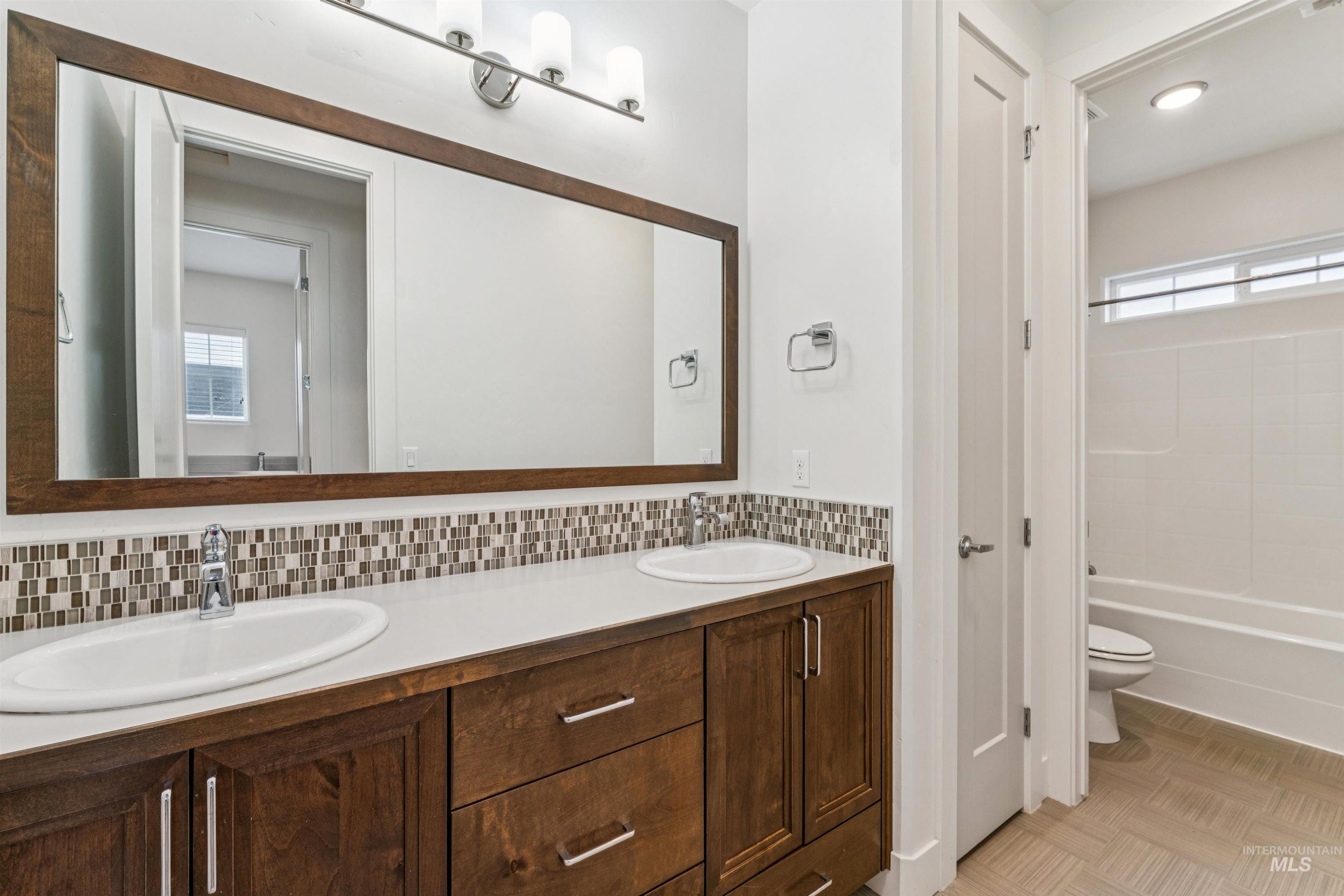 Full bathroom featuring double vanity, tasteful backsplash, and  shower combination