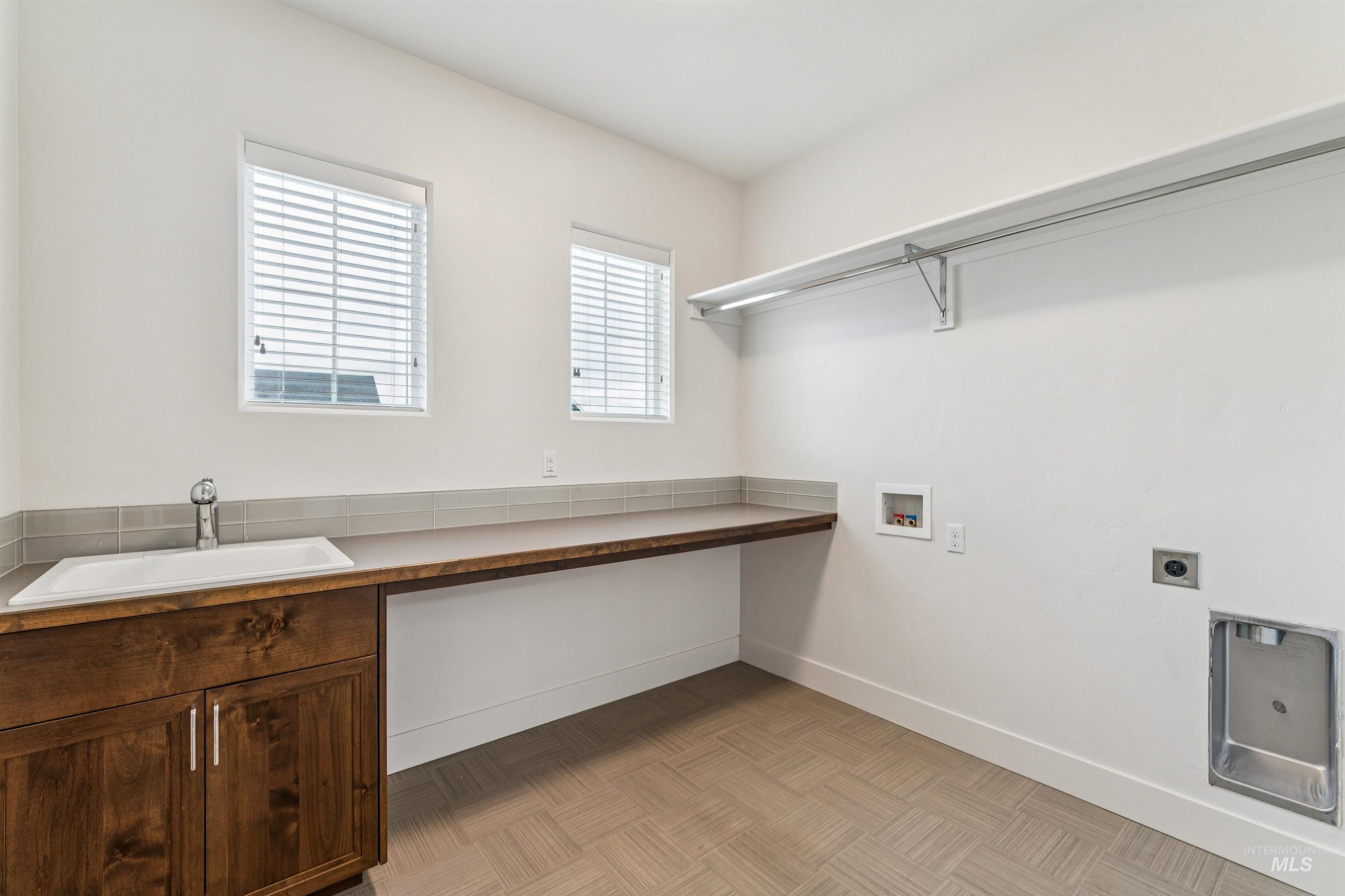 Laundry area featuring hookup for a washing machine, hookup for an electric dryer, folding counter and sink.