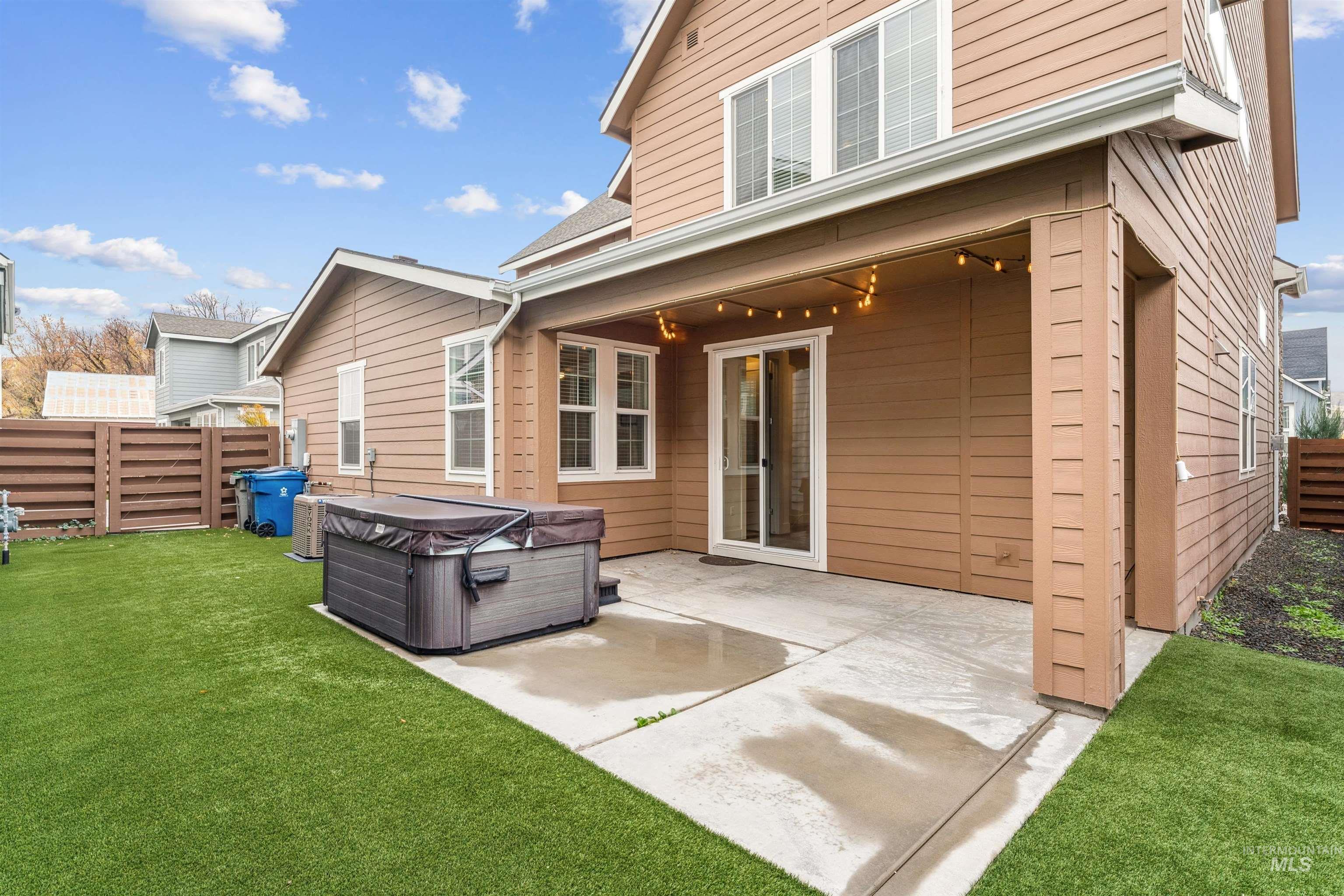Rear view of property featuring a fenced backyard, a patio, and a hot tub