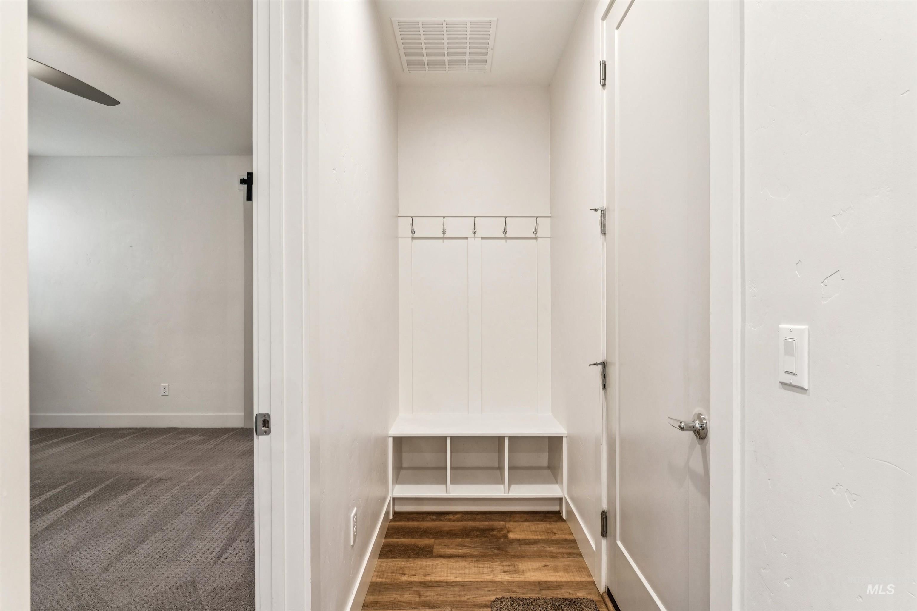 Mudroom with built-in coat hanger, shoe storage and adjacent coat closet.