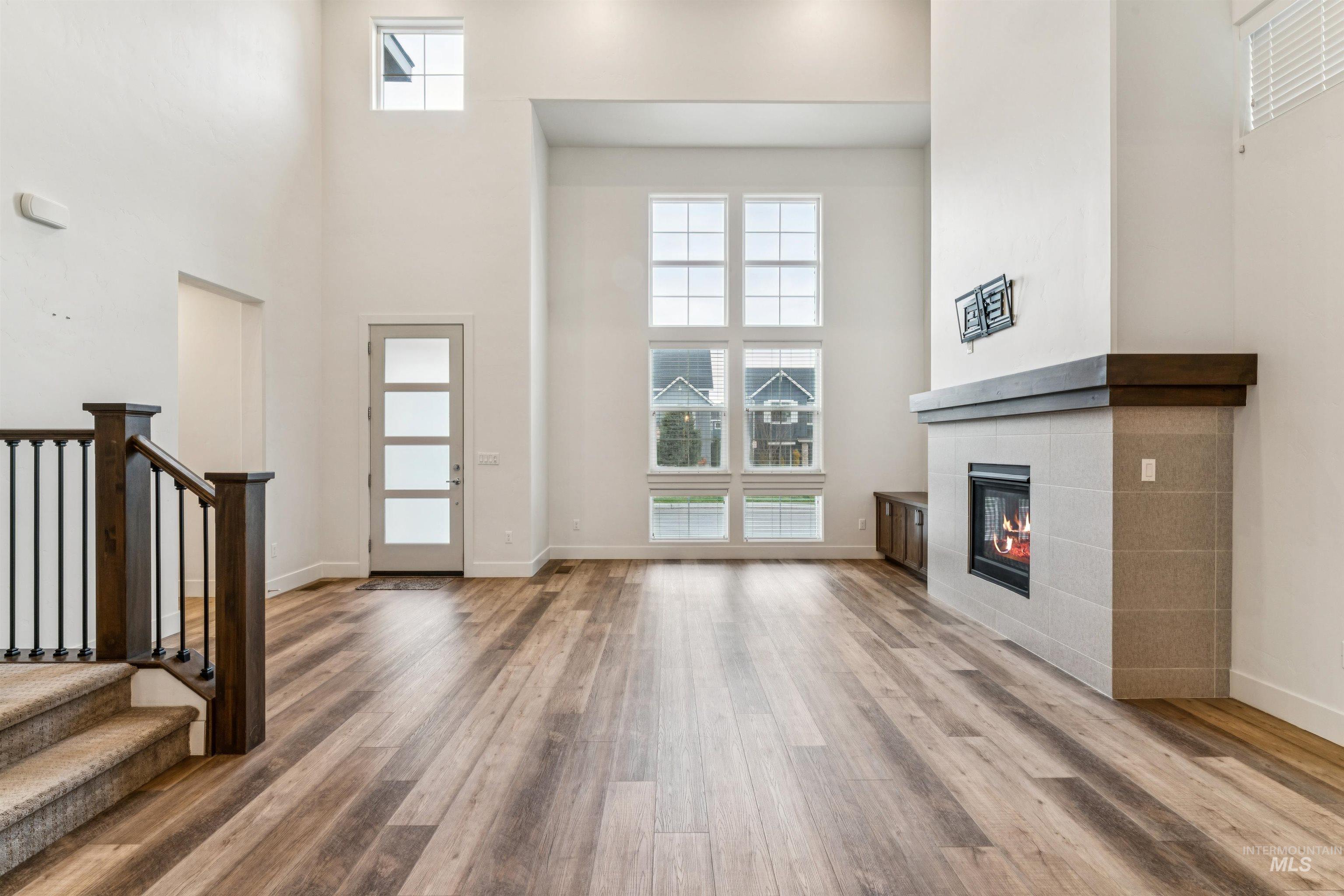 Living room with healthy amount of natural light, a towering ceiling, a tiled fireplace and luxury vinyl plank floors