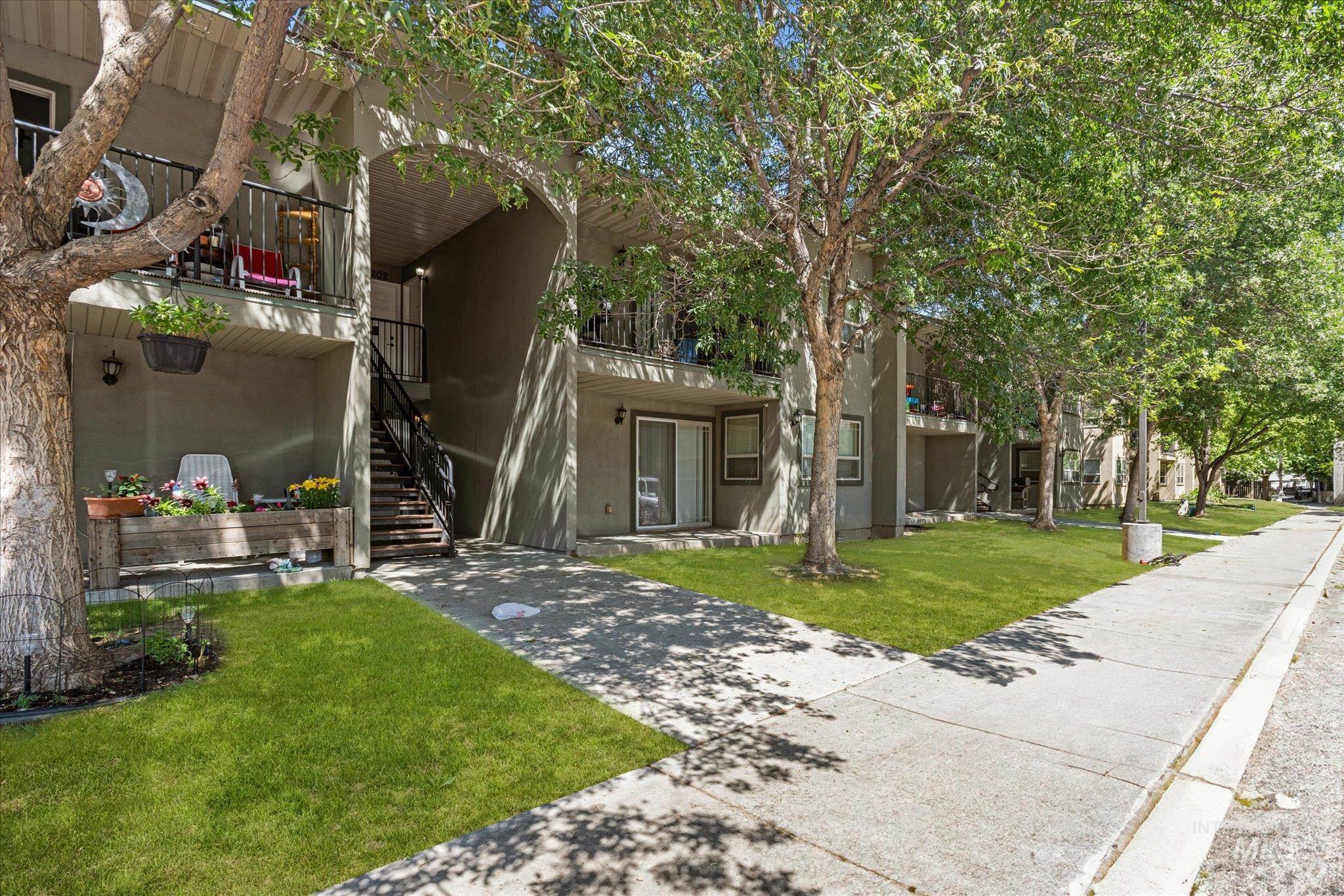 View of front of home with stairs, a balcony, a front lawn, and stucco siding