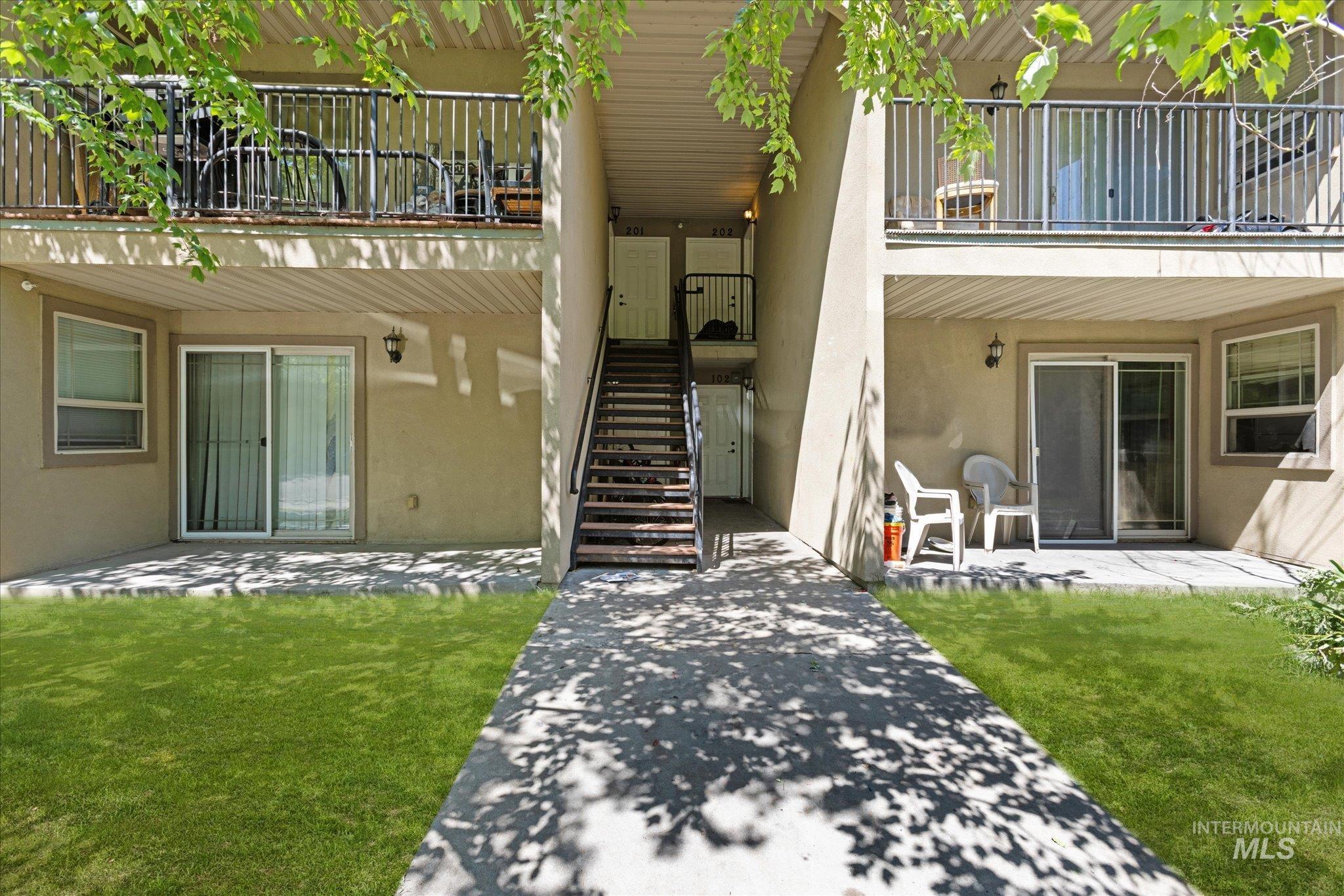 Property entrance featuring a balcony, stucco siding, a patio area, and a yard