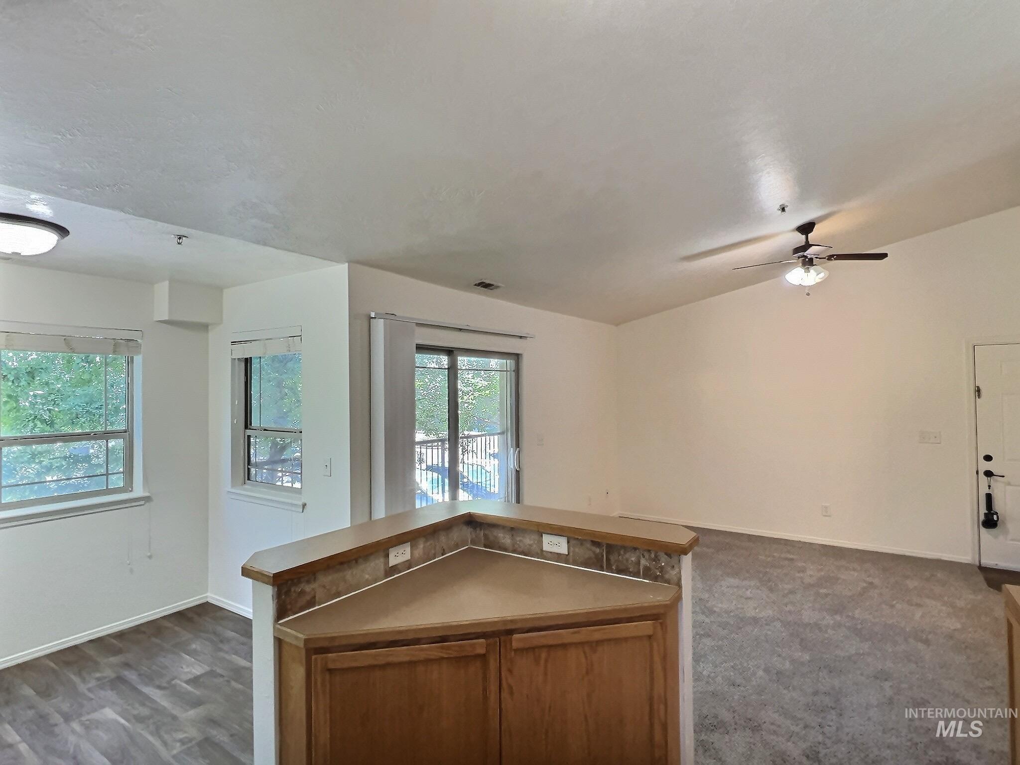 Kitchen featuring open floor plan, a center island, brown cabinets, light countertops, and ceiling fan