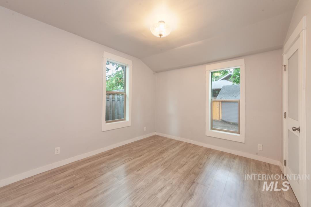 Unfurnished bedroom featuring light wood-style floors and lofted ceiling