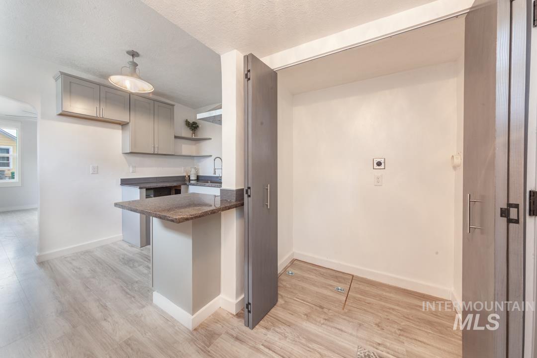Kitchen featuring open shelves, gray cabinetry, light wood finished floors, a peninsula, and a textured ceiling