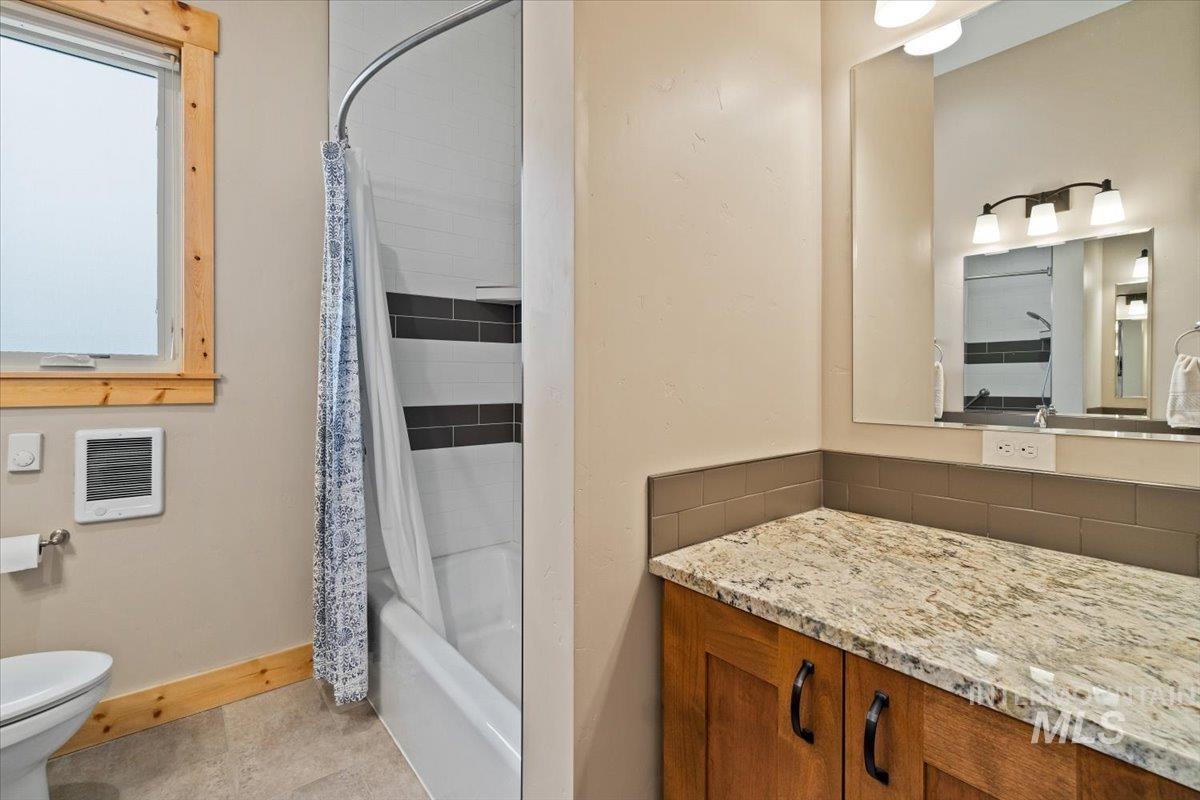 Bathroom with heating unit, vanity, tasteful backsplash, and shower / bath combo with shower curtain