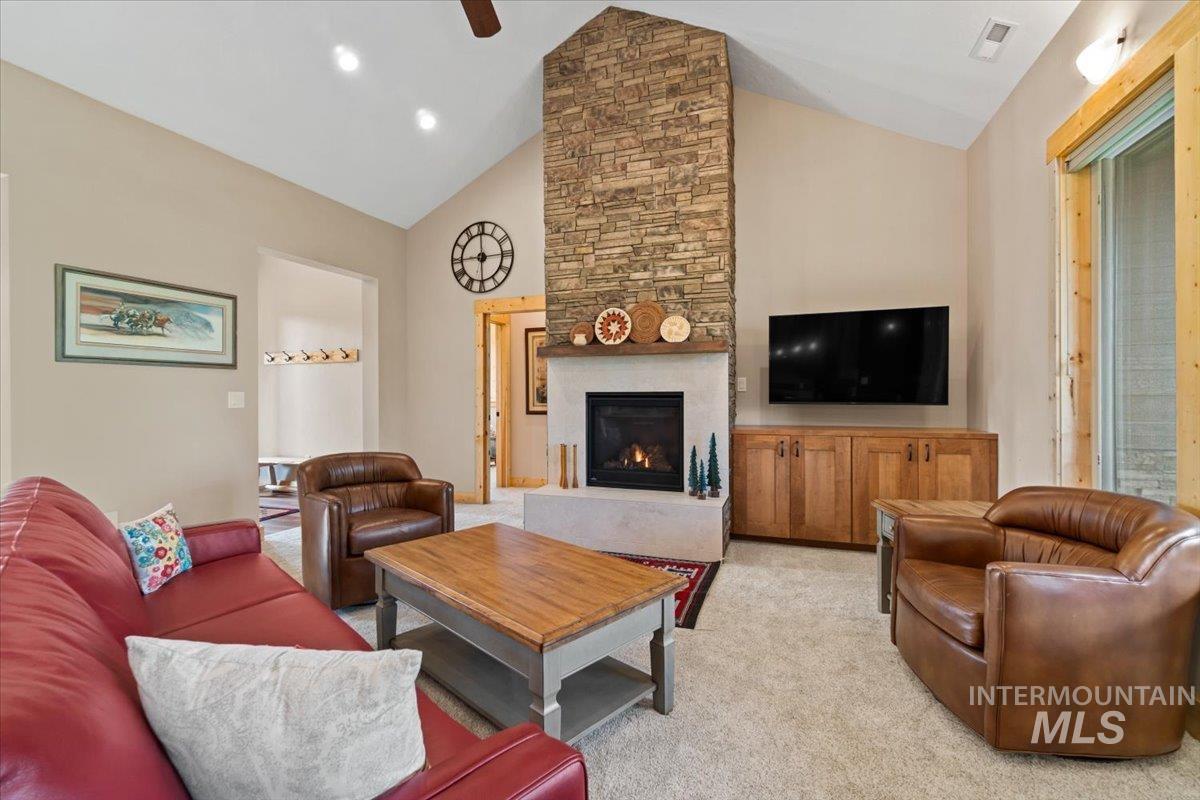 Living area with light carpet, a large fireplace, and high vaulted ceiling