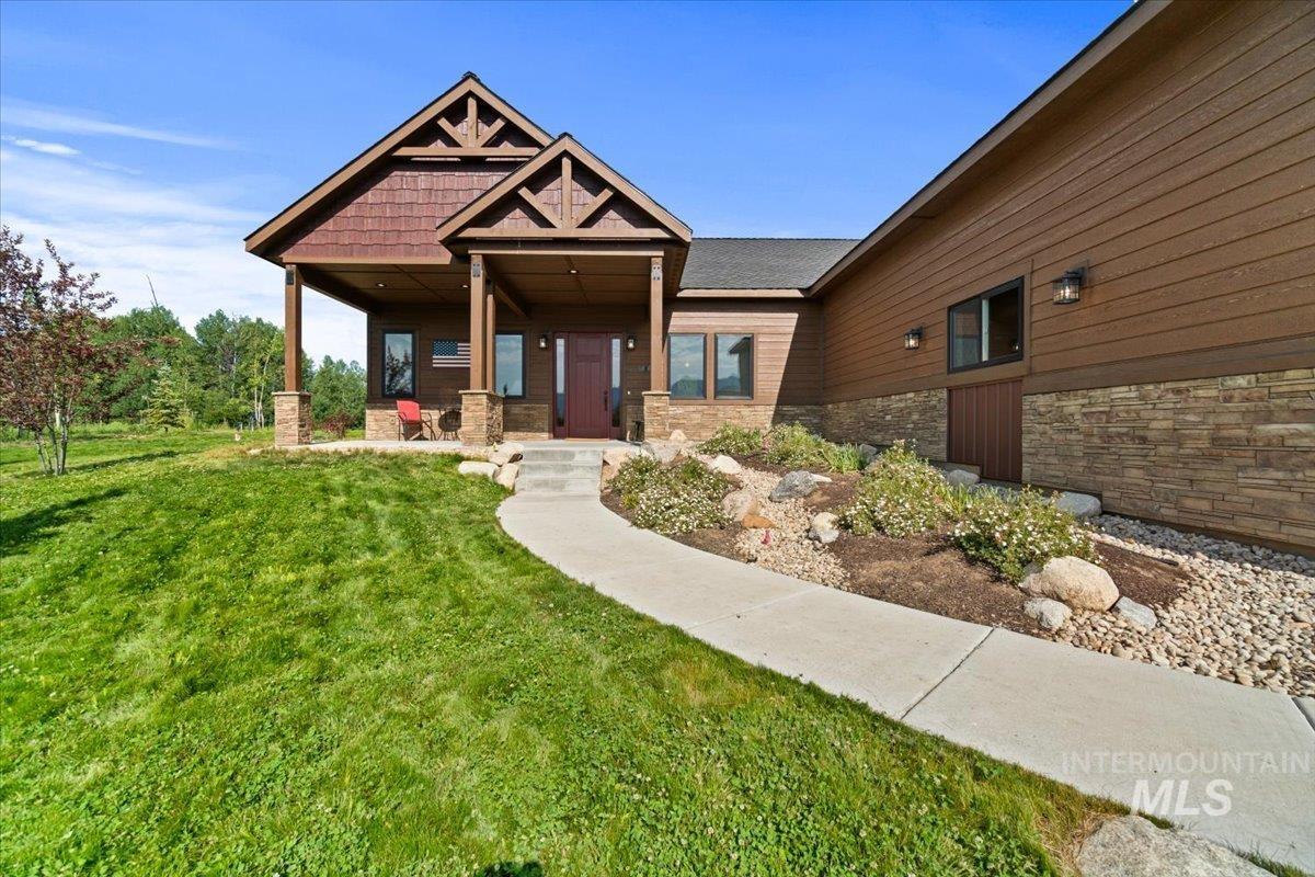 View of front of property featuring stone siding, a front lawn, and covered porch