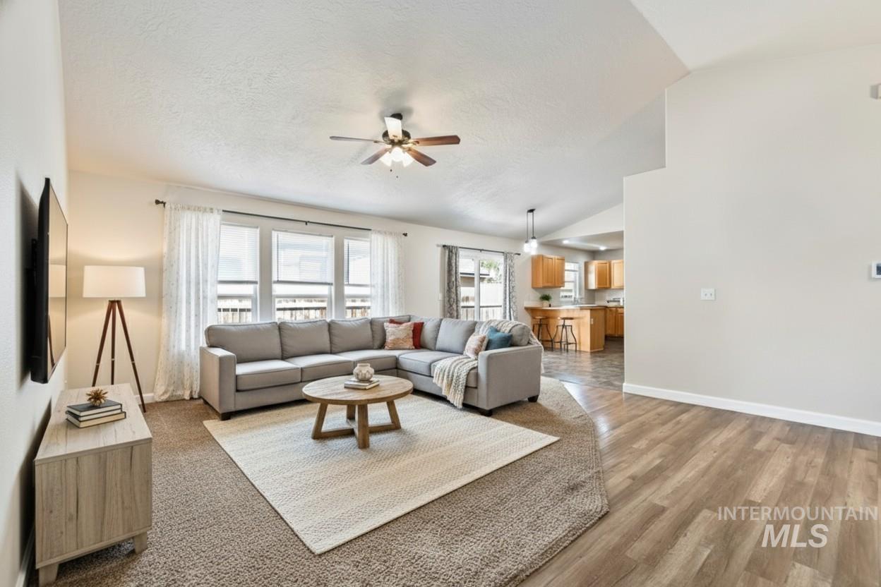 Living area featuring ceiling fan, light wood-style flooring, and lofted ceiling