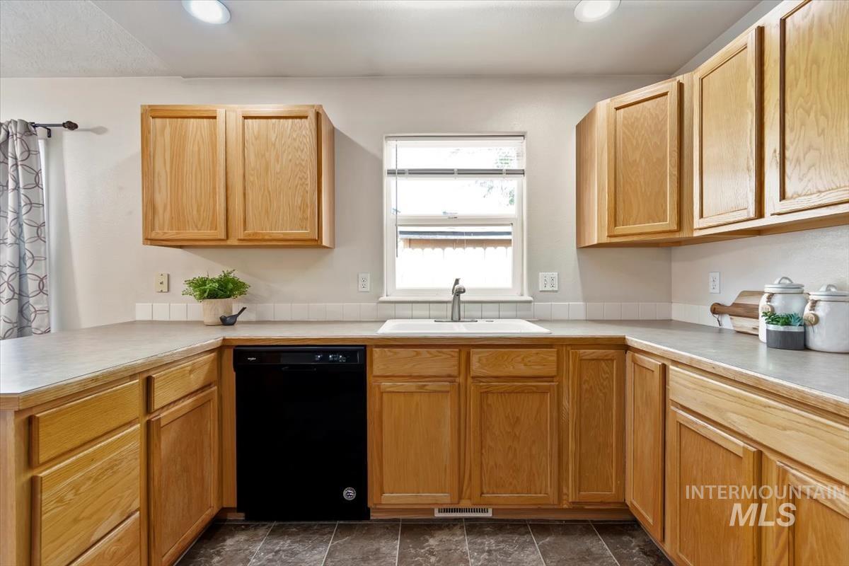 Kitchen featuring light countertops, dishwasher, light brown cabinetry, a peninsula, and recessed lighting
