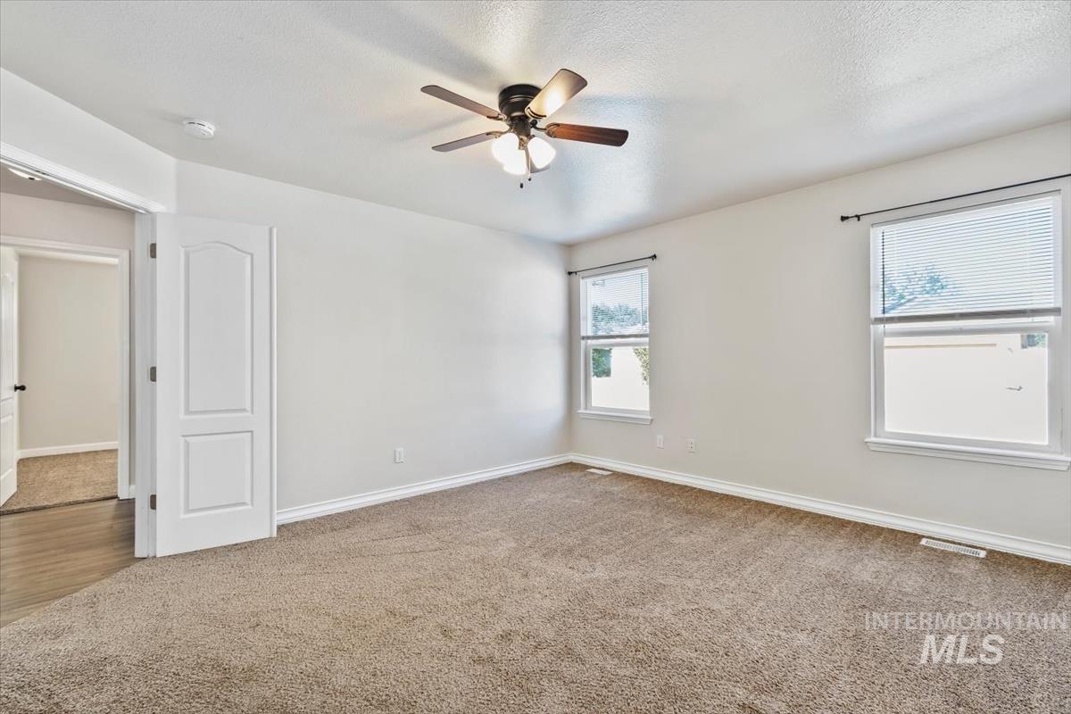 Spare room featuring light colored carpet, ceiling fan, and a textured ceiling