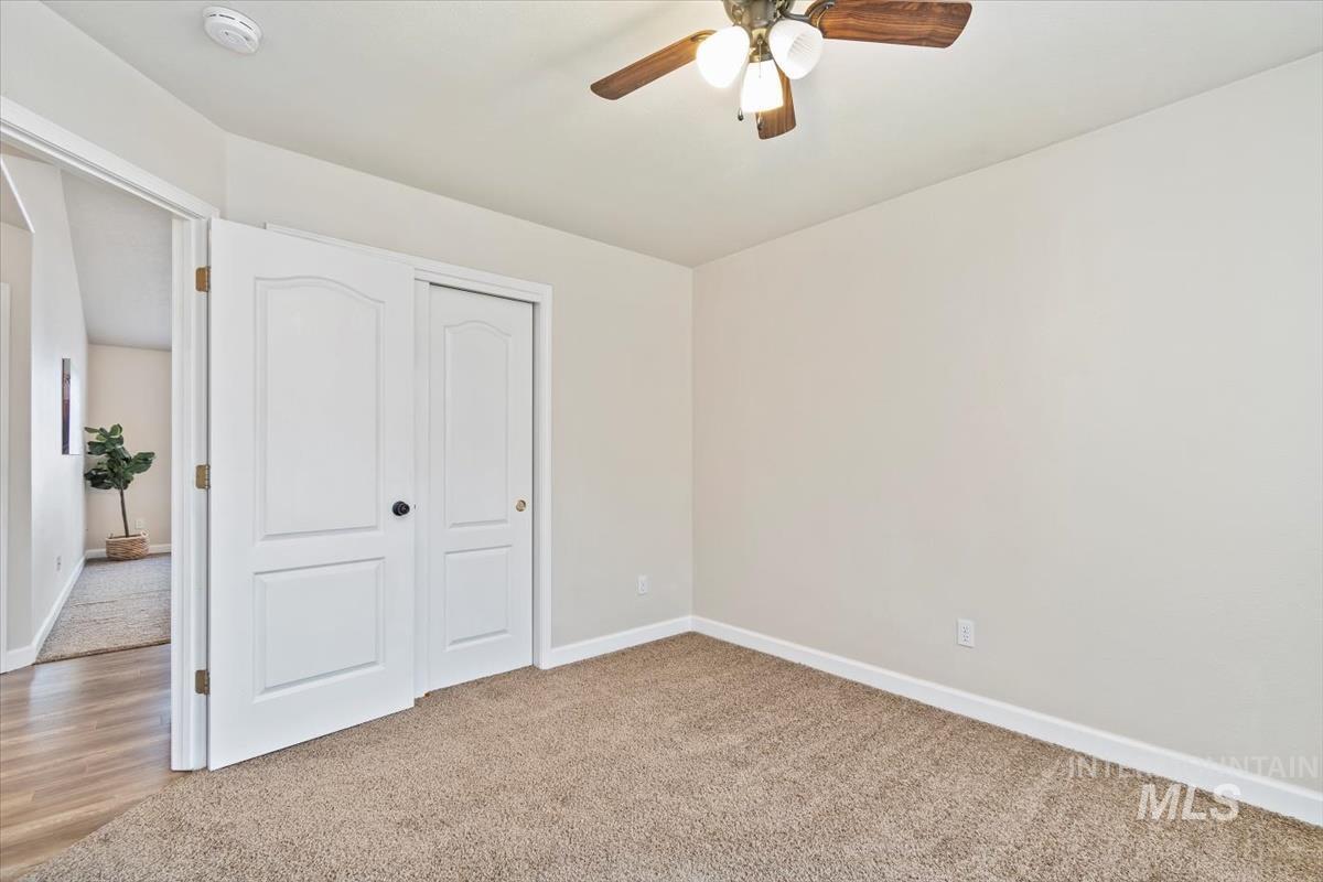 Unfurnished bedroom featuring light colored carpet, a closet, and a ceiling fan
