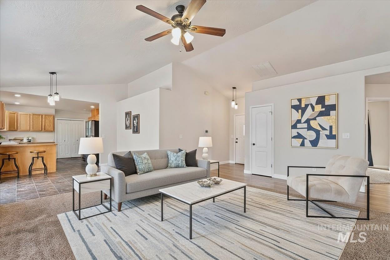 Living area with vaulted ceiling, ceiling fan, and light colored carpet
