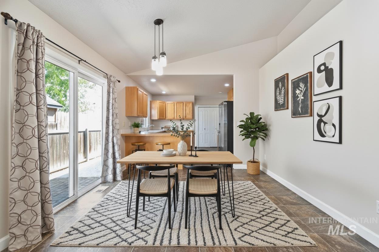 Dining room featuring vaulted ceiling, stone tile flooring, and recessed lighting